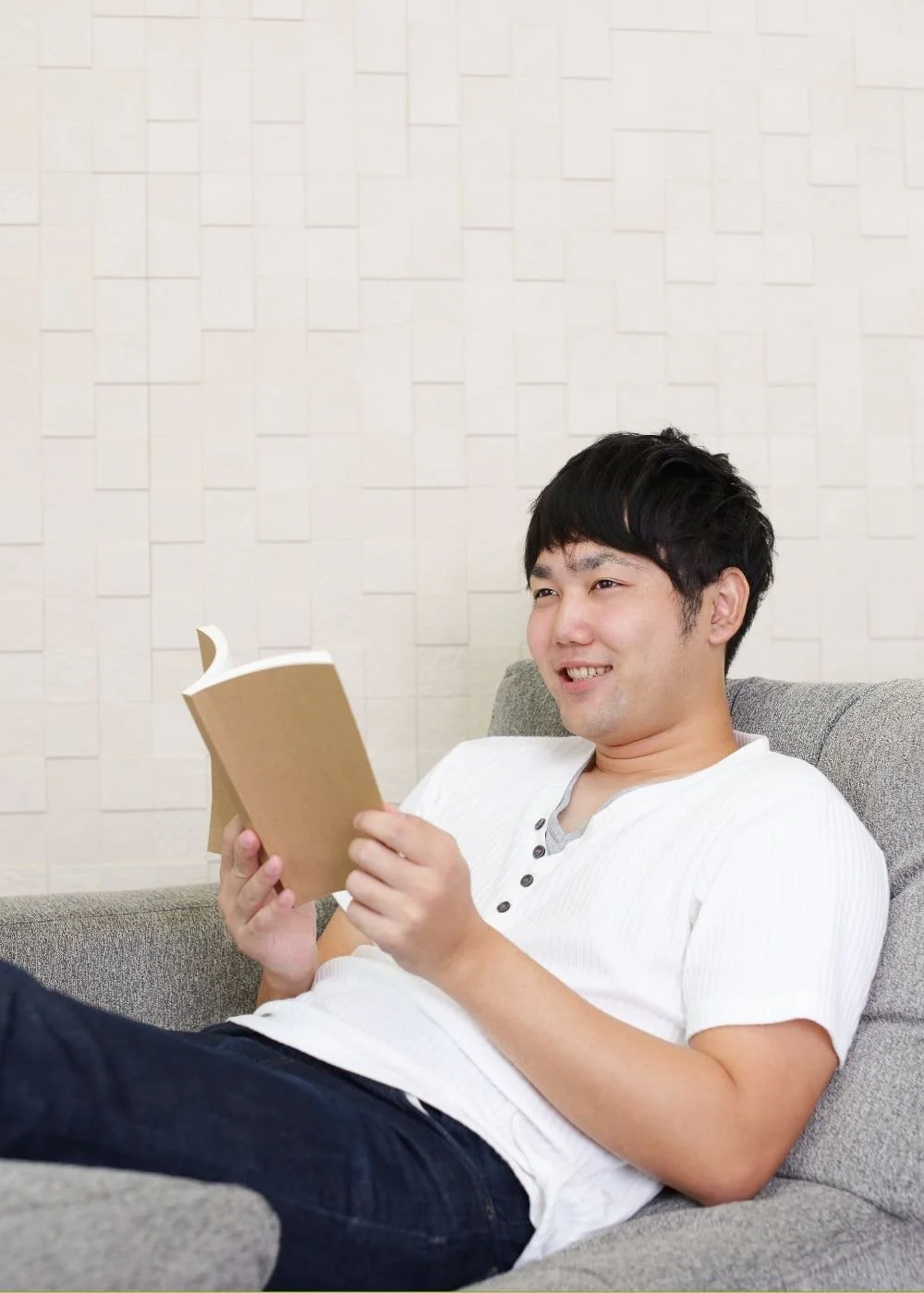 A picture of a man sitting on the couch reading a book.