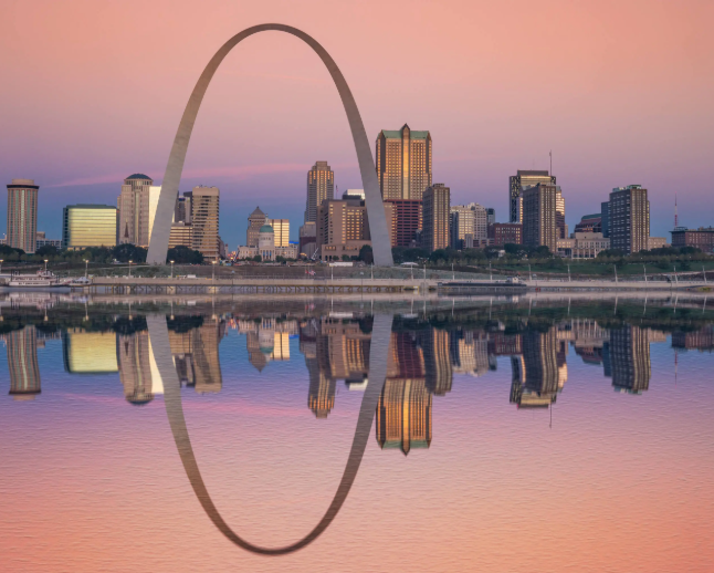 Sunset over downtown St. Louis with the Gateway Arch and city skyline reflected in the river.