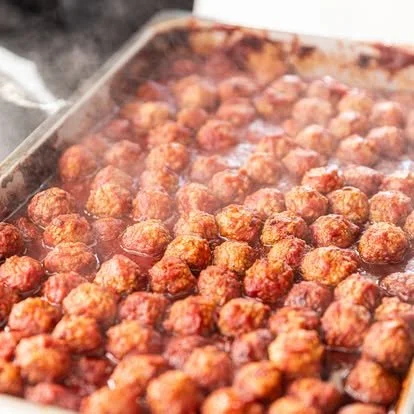 Cooking meatballs in a baking dish with sauce.
