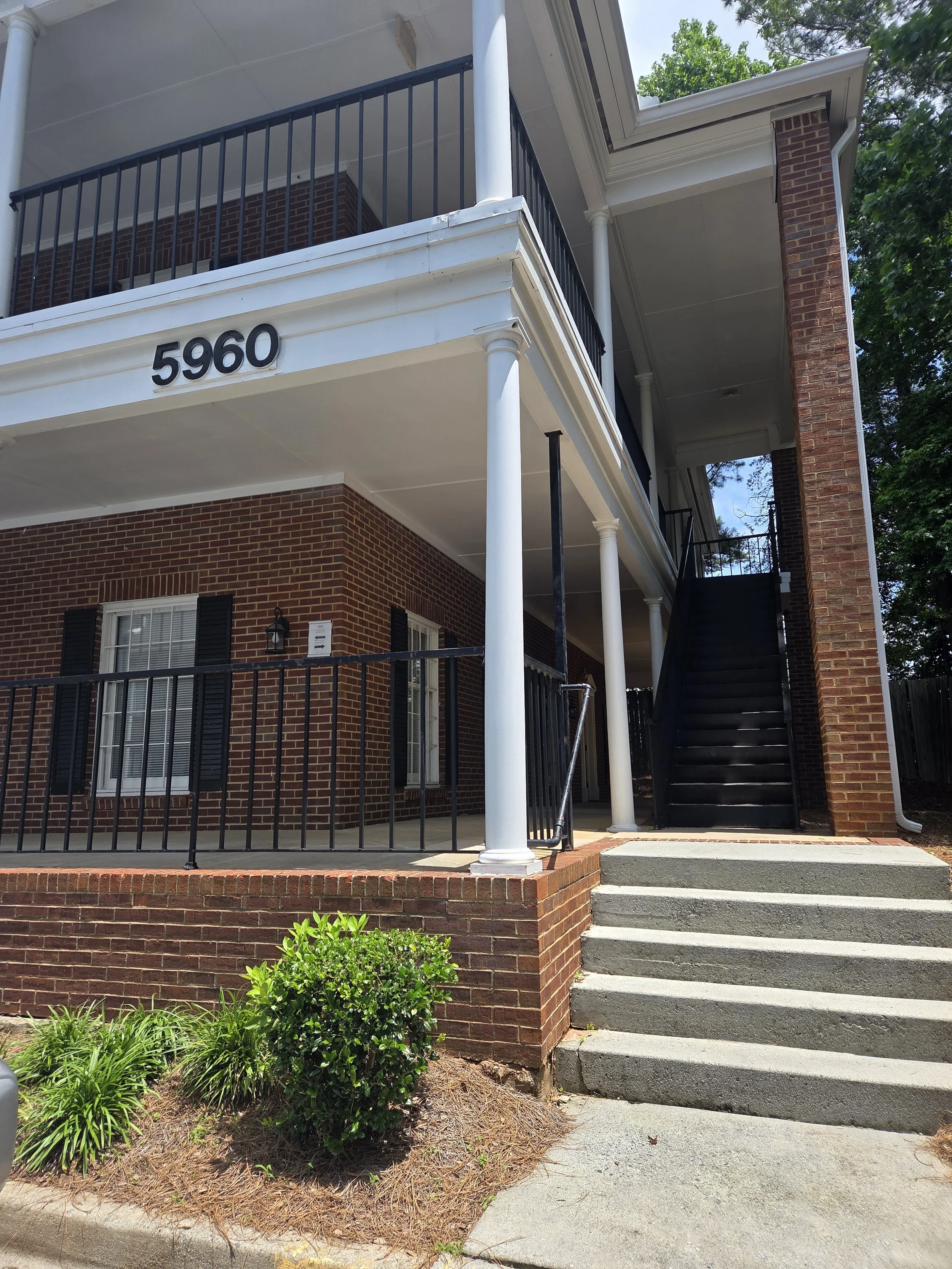 Entrance for Kaleidoscope Counseling & Consulting. Mike Weiland, kscopecc located Two-story brick business building with white trim and the number 5960 on the front. There are concrete stairs leading to a black staircase on the right side.