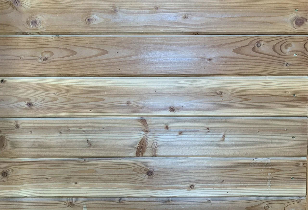 A close-up view of a wooden wall with horizontal planks showing natural wood grain and knots.