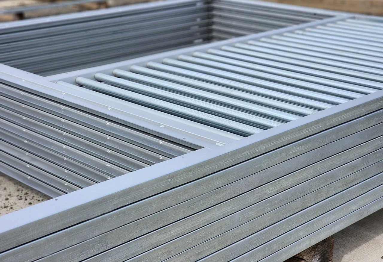 Close-up of stacked aluminum materials, including slats and curved rods, outdoors.