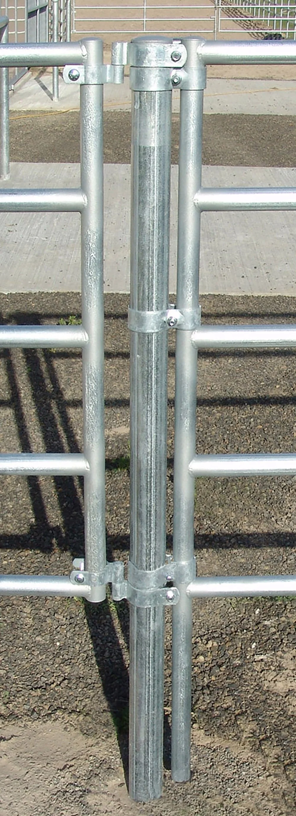 Close-up of a metal gate latch mechanism on a playground fence, showing vertical and horizontal metal bars with bolts and clamps.