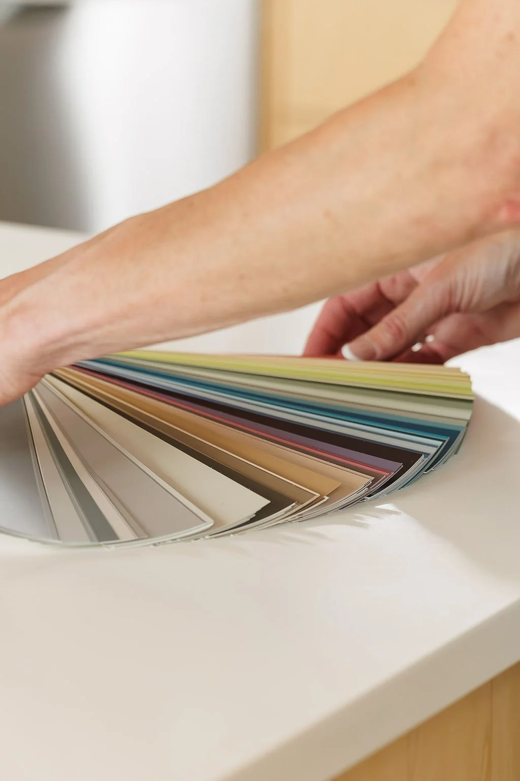 A person flipping through a color sample book with painted color swatches in various shades.