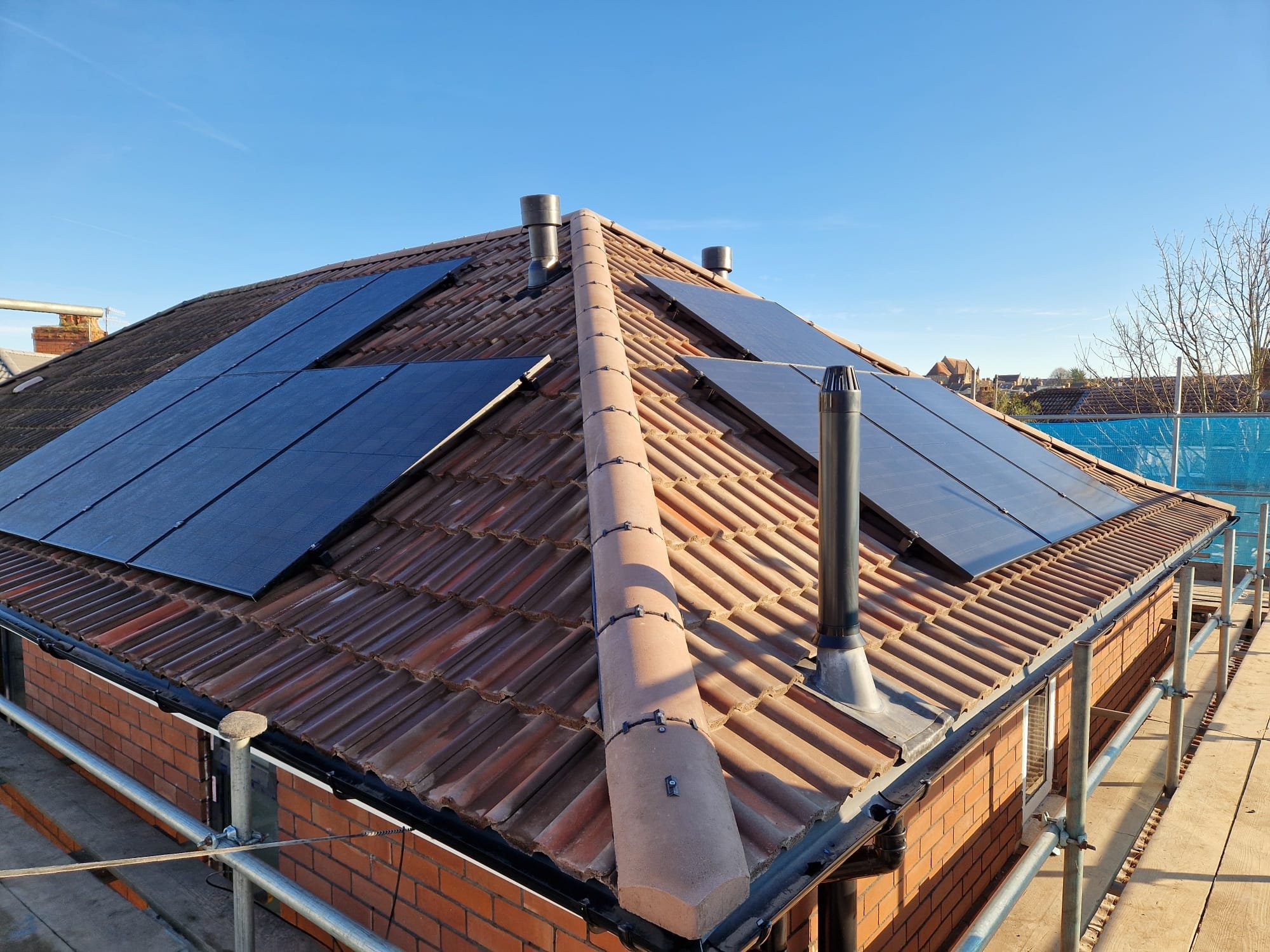 House roof with solar panels and chimney on a sunny day