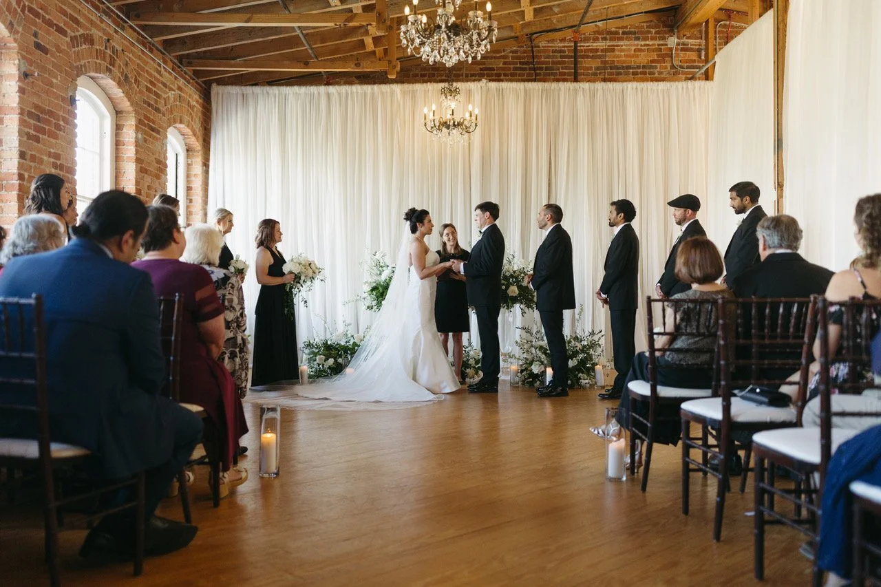 Wedding officiant with bride and groom and guests for a wedding at an historic knitting mill in Raleigh NC