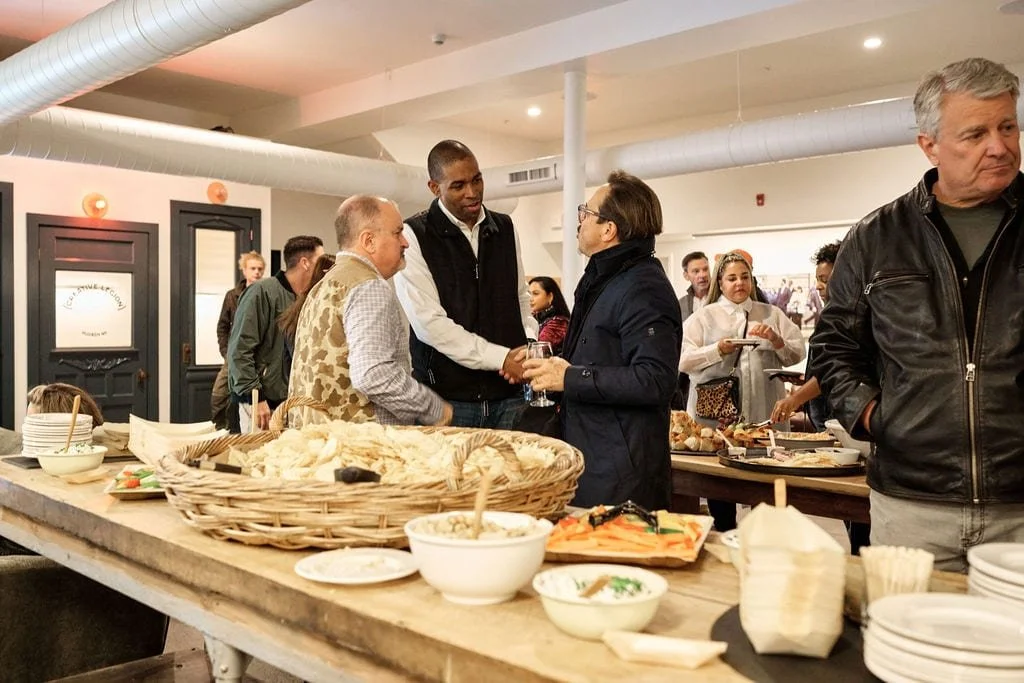 People socializing at a buffet table with food in a restaurant or café setting.