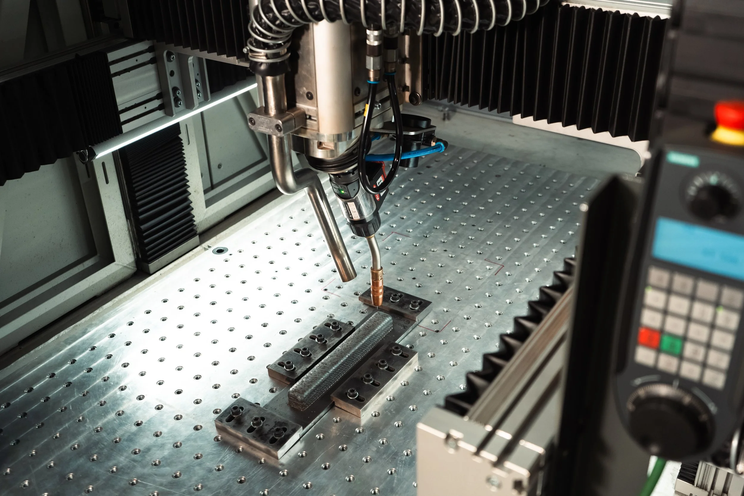 Industrial CNC machine with robotic arm using laser cutting technology on metal surface, control panel visible.