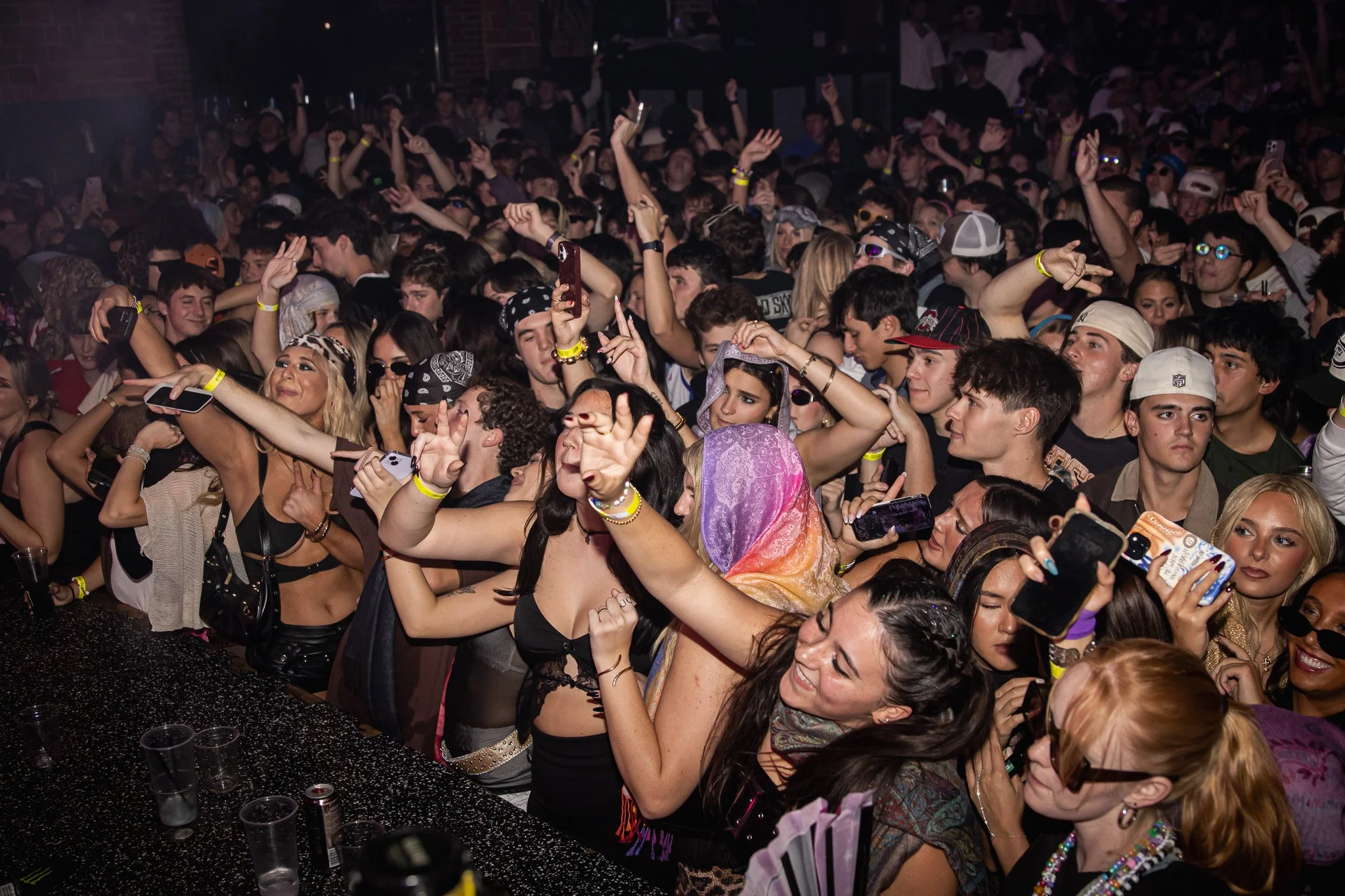 Crowd of people dancing and taking photos at a concert or music festival.