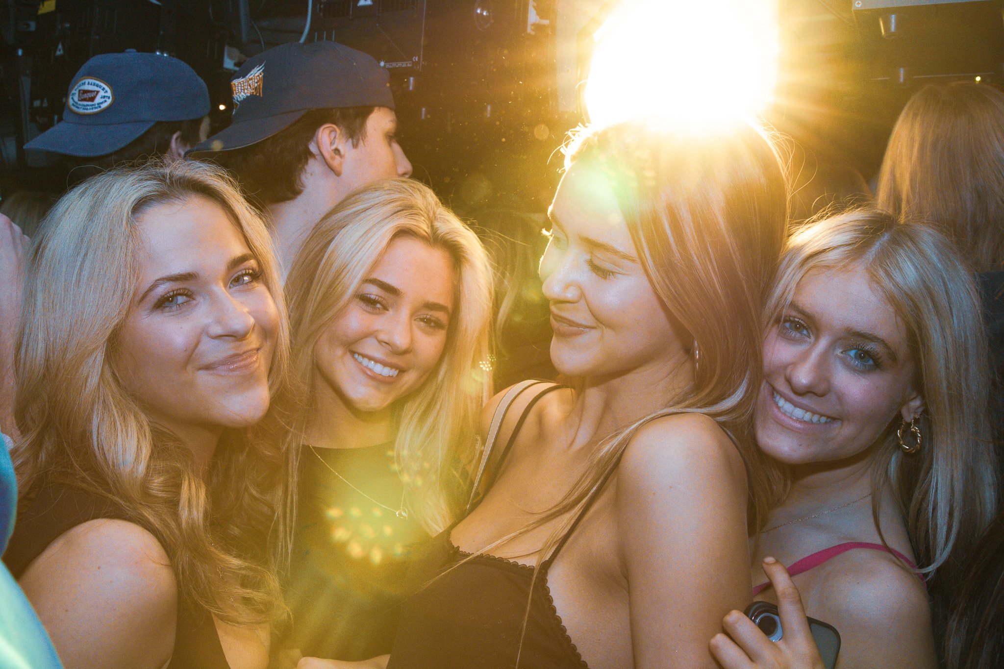 Group of young women smiling and enjoying themselves at a party, with sunlight shining in the background.