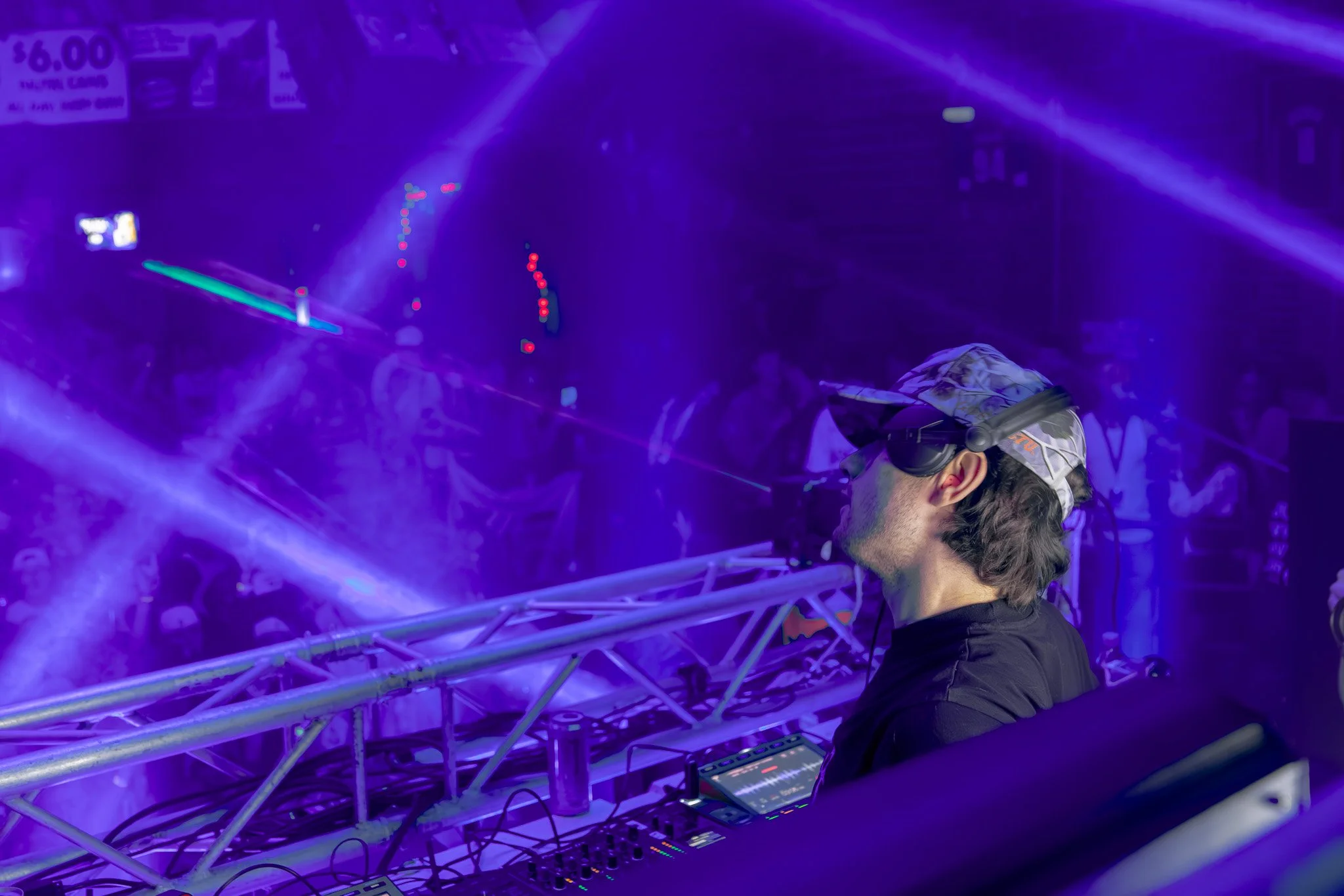 DJ performing with purple and blue laser lights in a club or music venue.