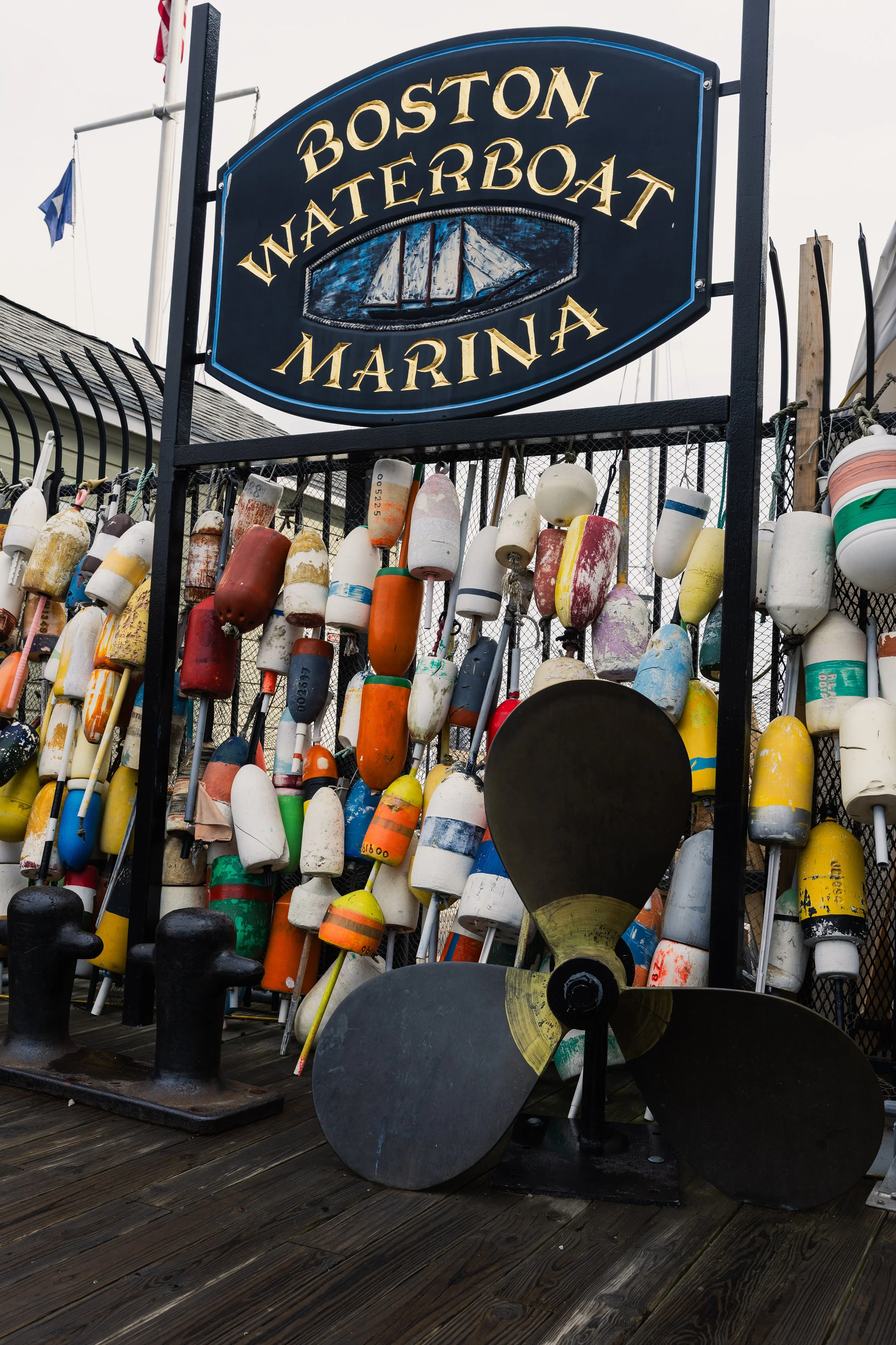 Sign reading 'Boston Waterboat Marina' with boating buoys and a boat propeller in front.