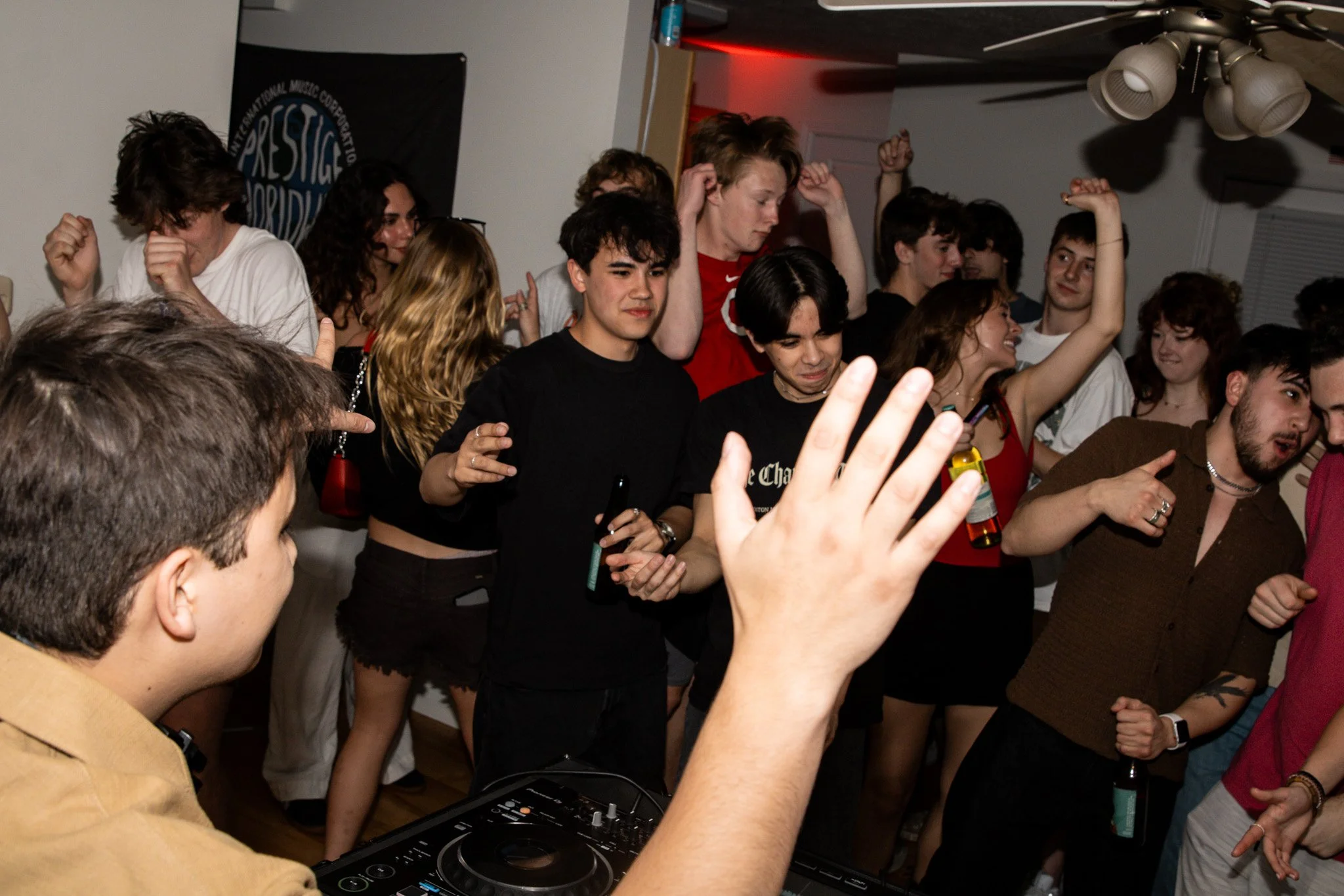 People dancing and enjoying music at a party with a DJ playing music.