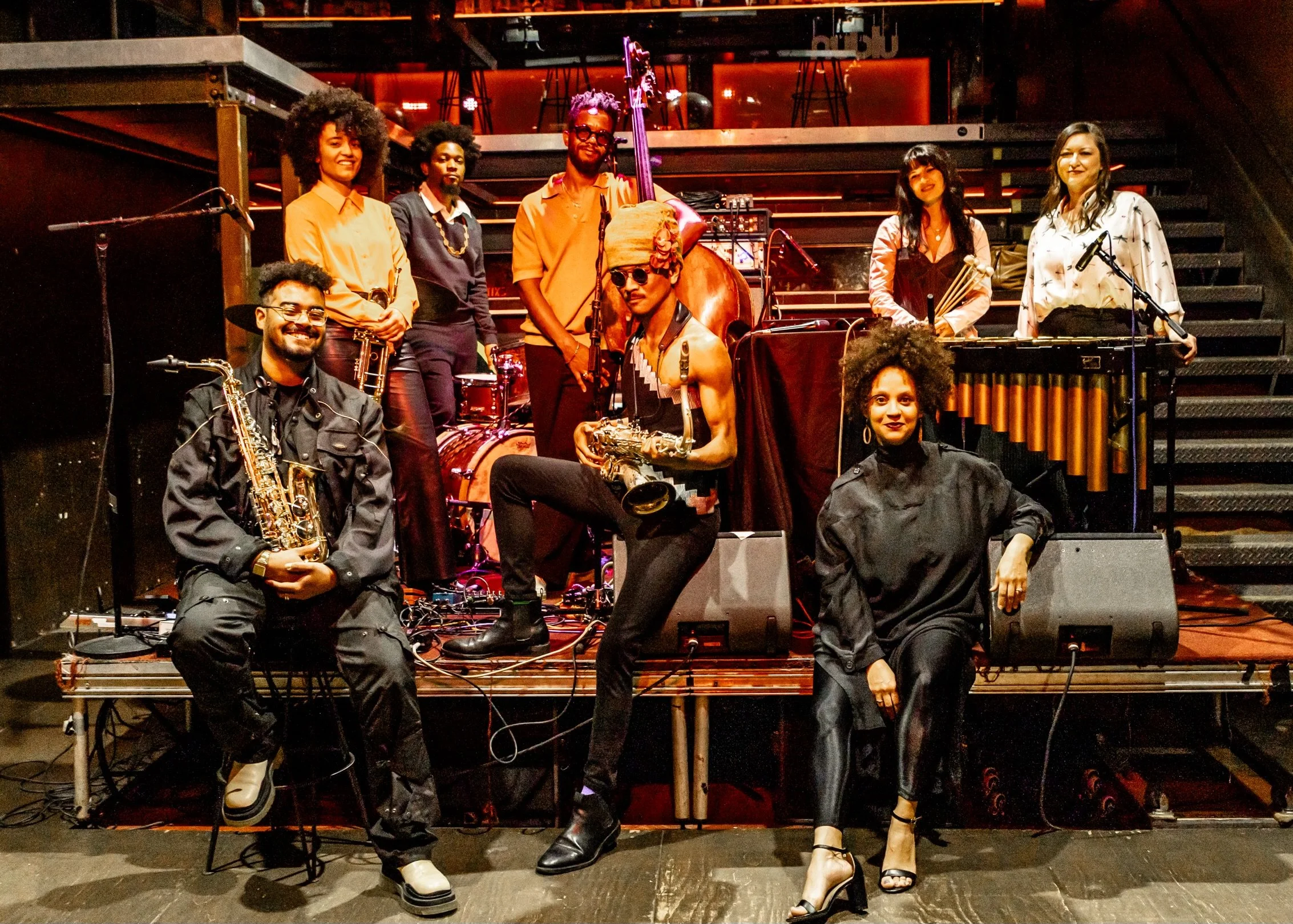 Group of musicians posing with their instruments on a stage.