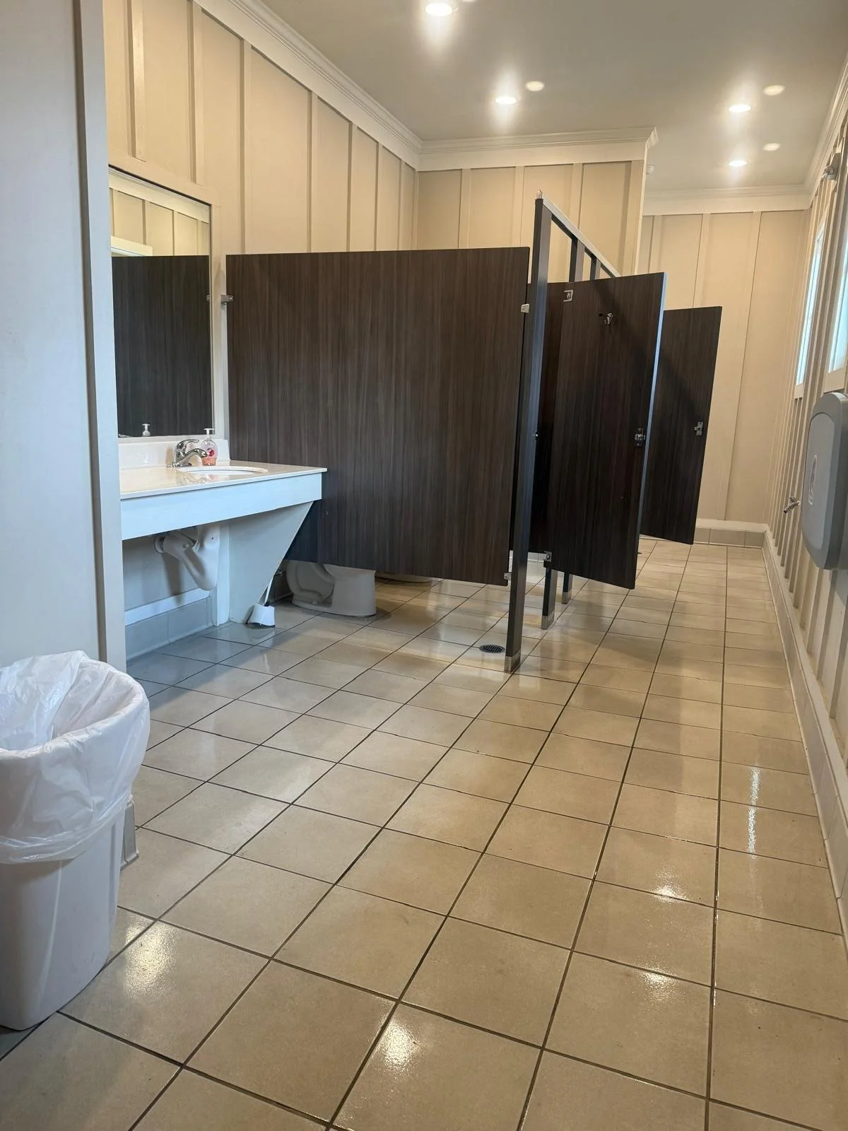 Clean commercial restroom with multiple stalls and sinks
