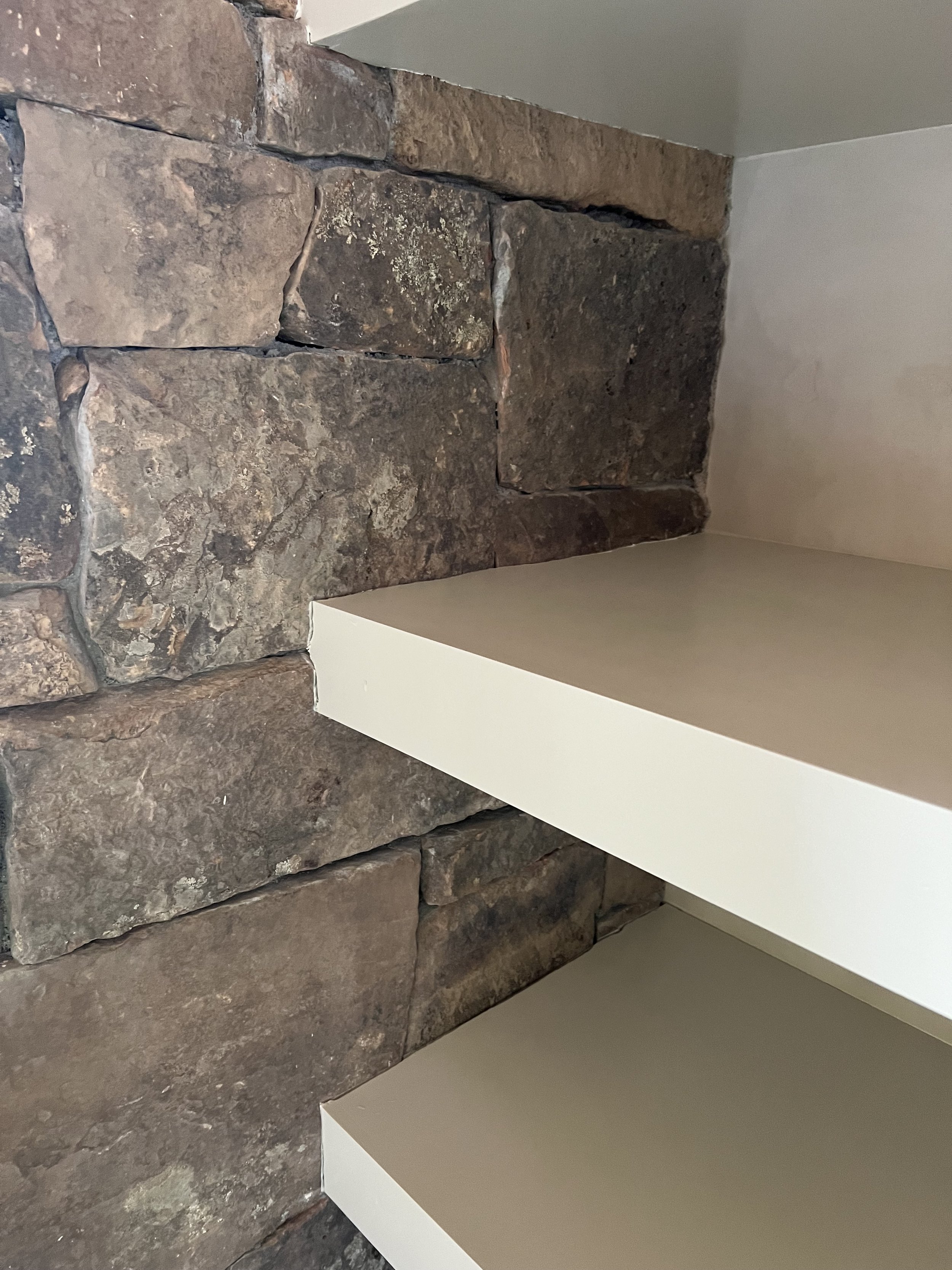 Stone wall corner with two beige shelves