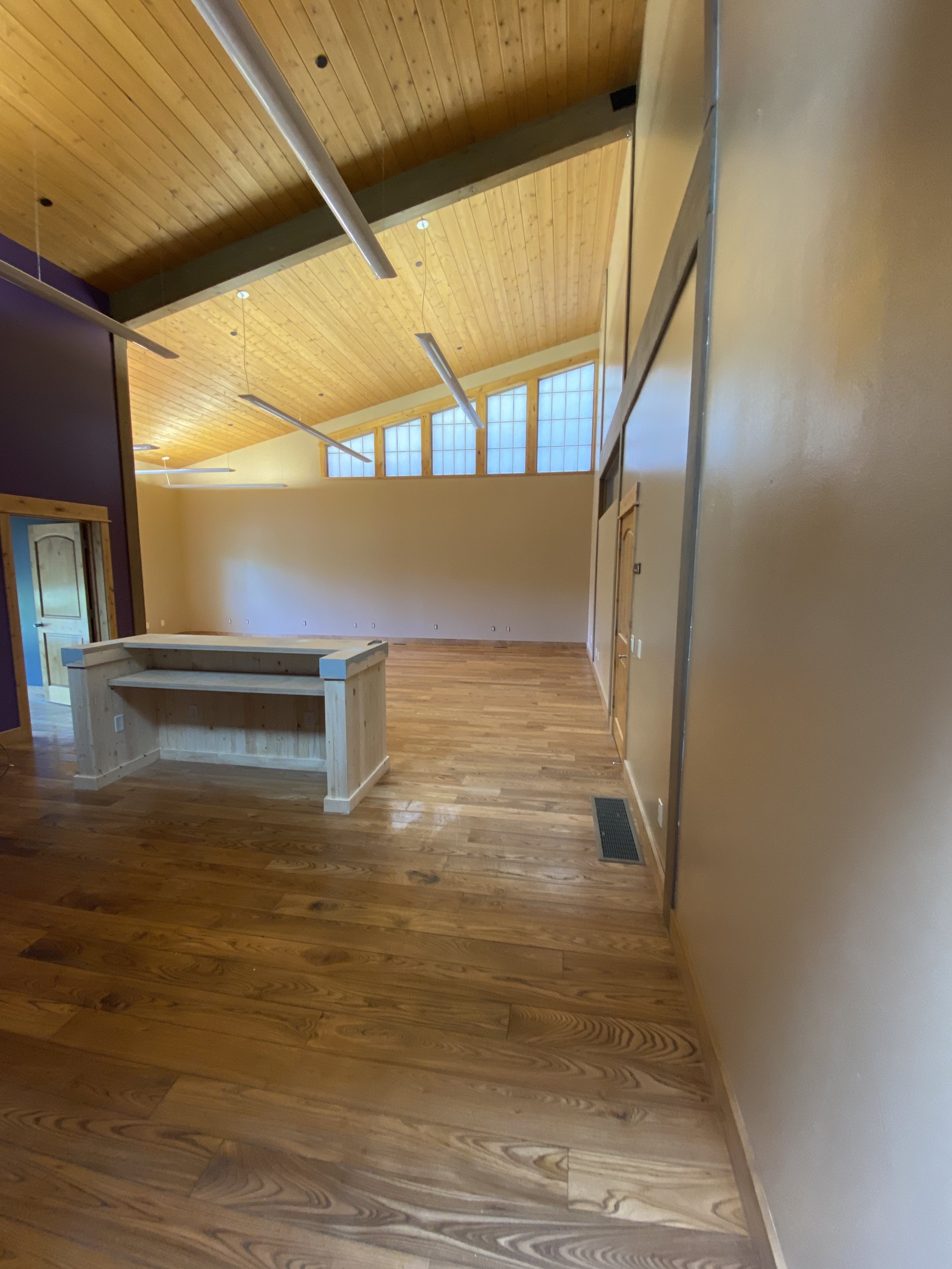 Empty room with wooden floors, high ceiling, and a counter