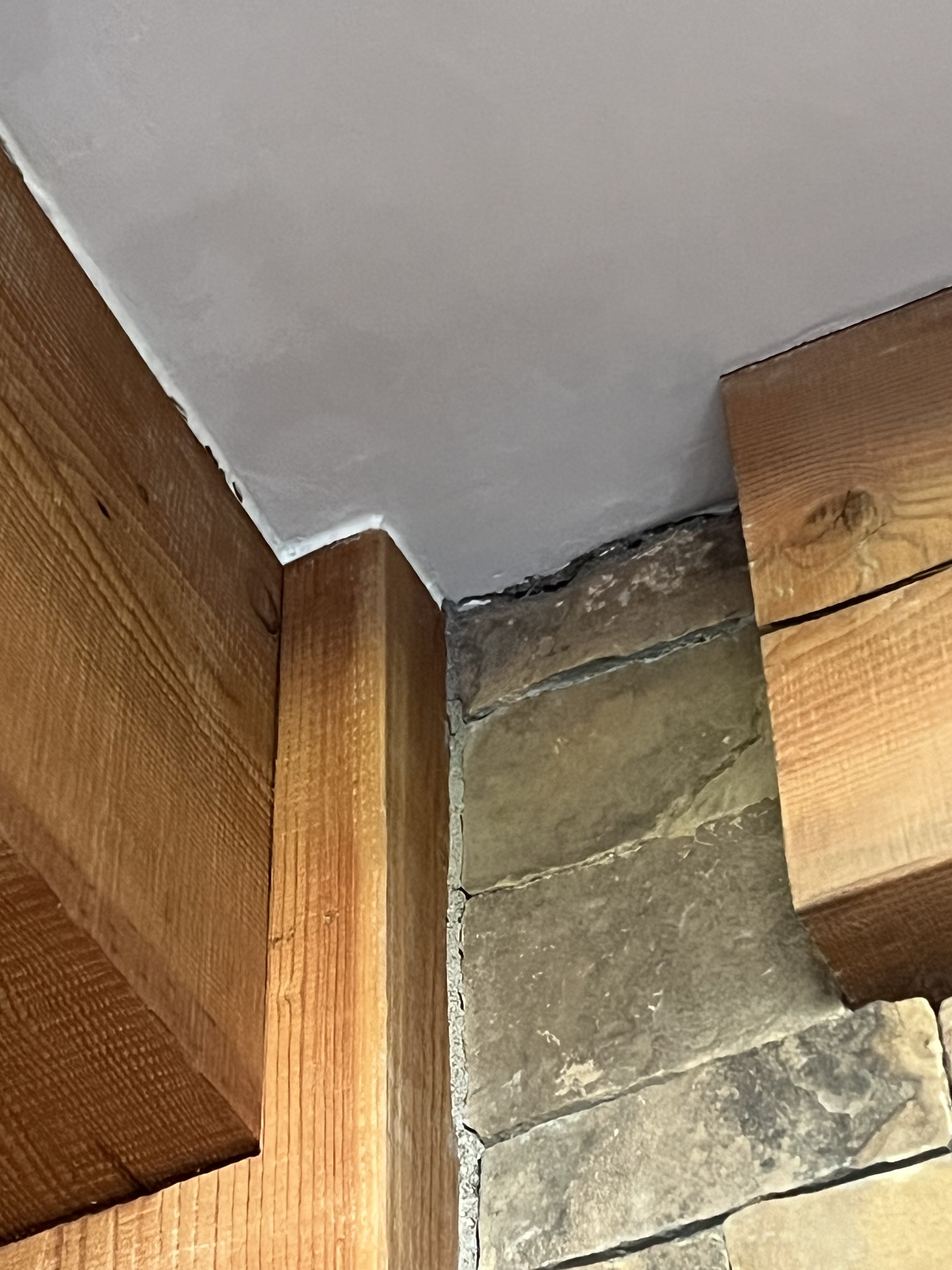 Close-up of corner with wooden beams, stone wall, and white ceiling