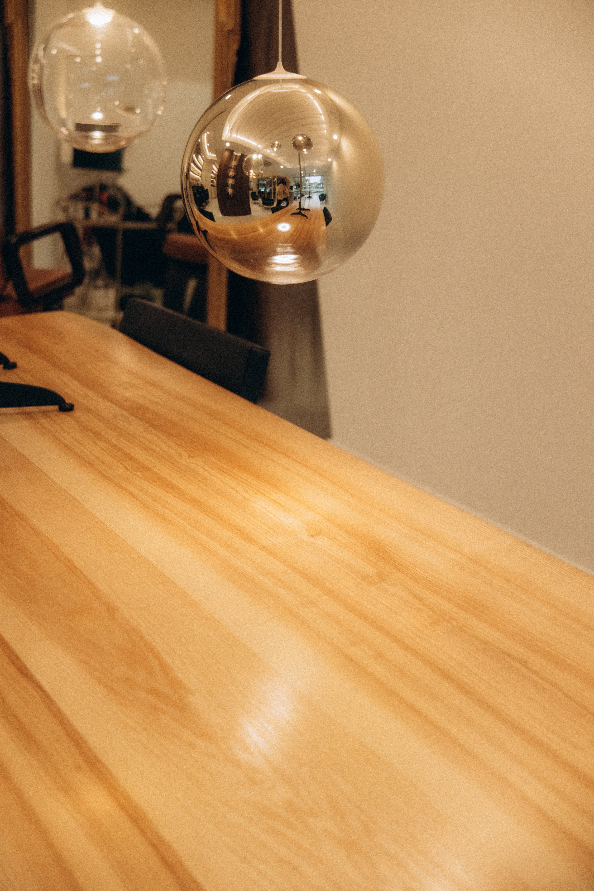 Deux pendentifs en forme de sphère, l'un en or brillant et l'autre en transparence, suspendus au-dessus d'une table en bois.