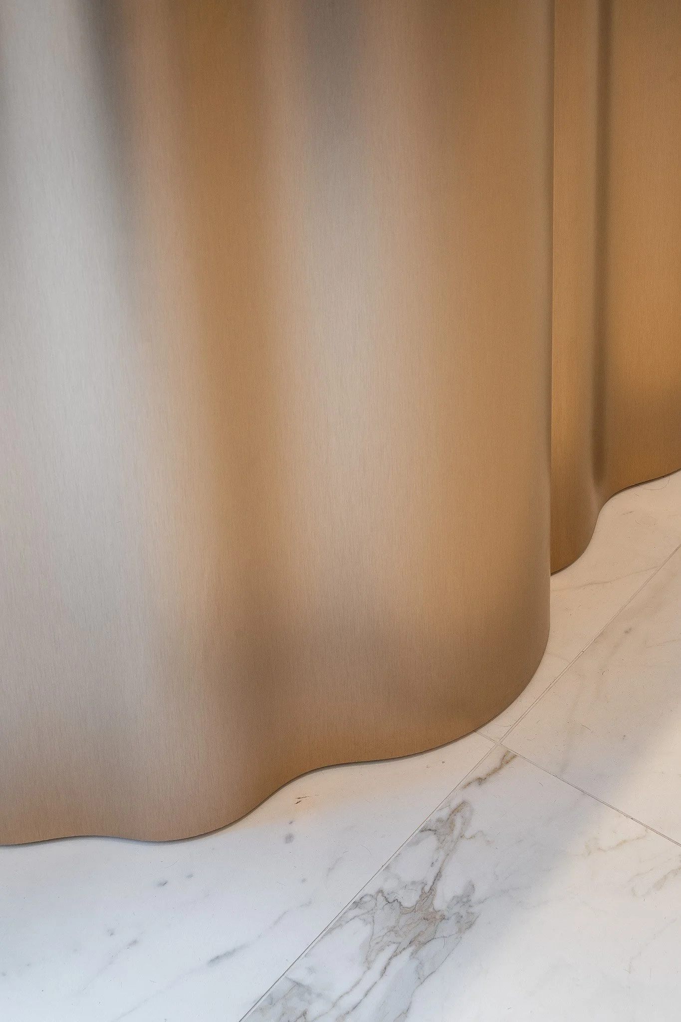 Détail d'une surface en métal doré ou bronze avec un sol en marbre blanc.