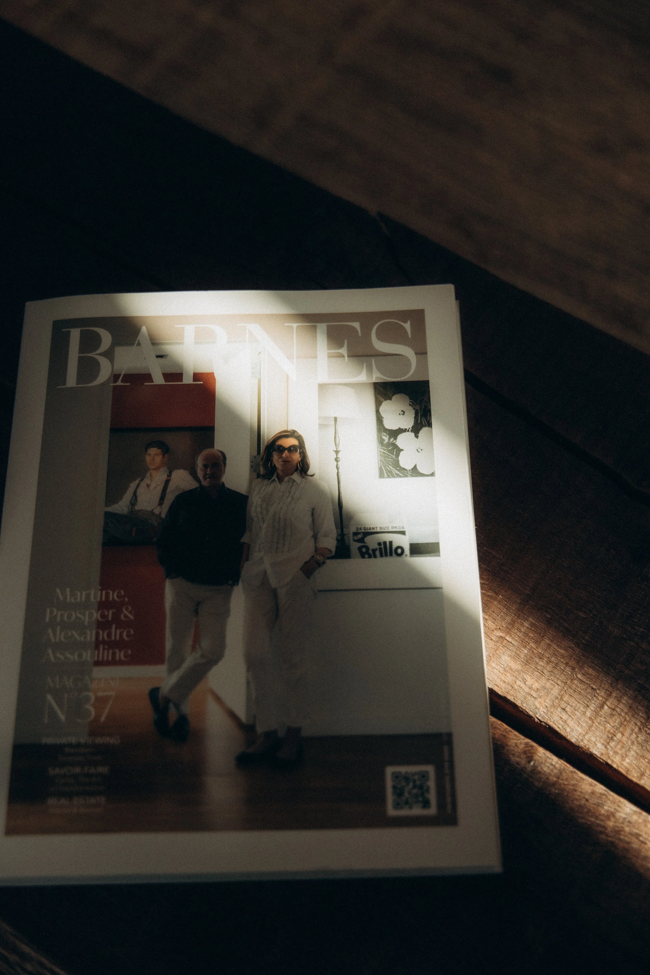 Une couverture de magazine avec deux personnes dans une pièce, une femme portant des lunettes de soleil et un homme, sans autres détails visibles.