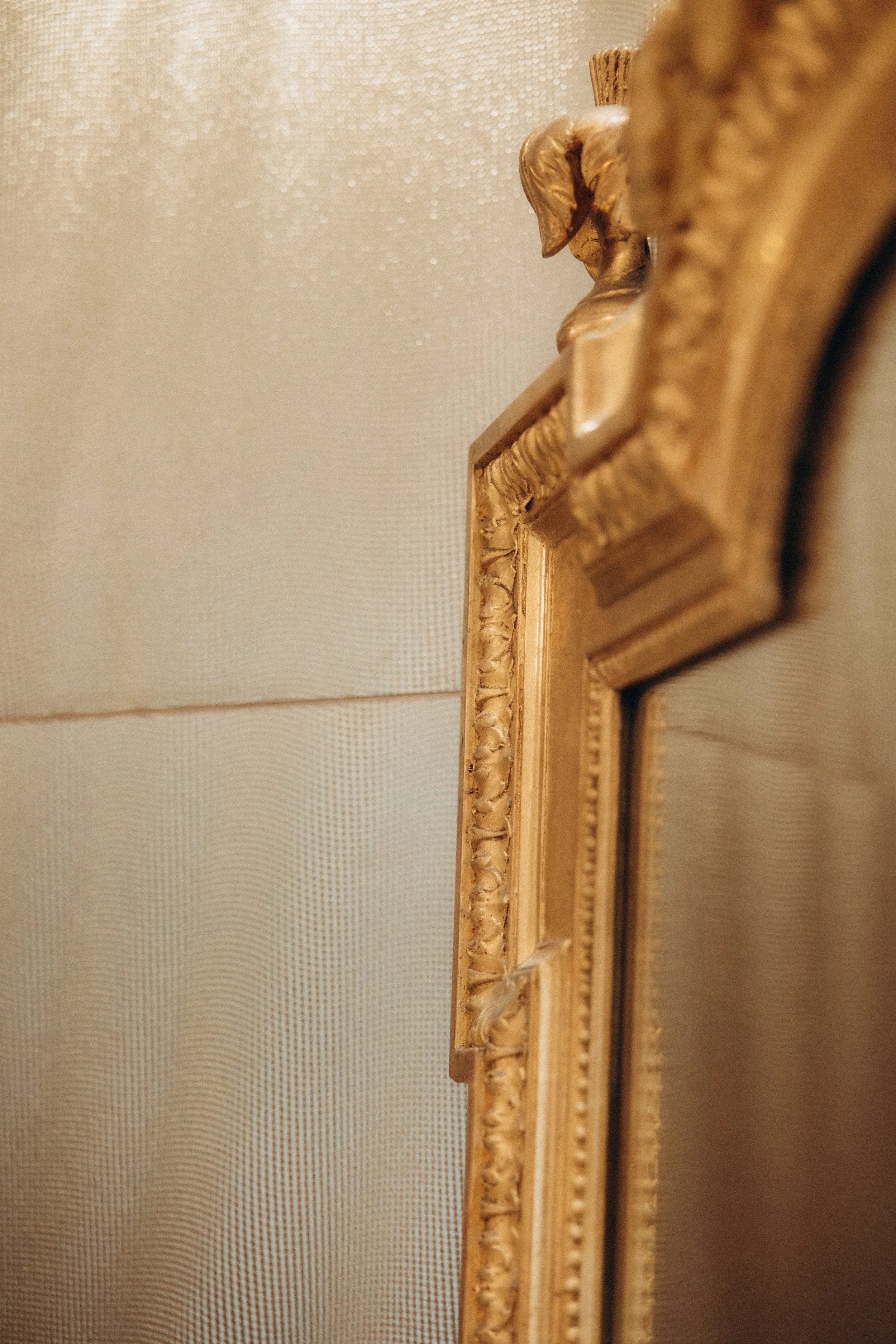 Photo d’un cadre doré orné de détails sculptés au mur.