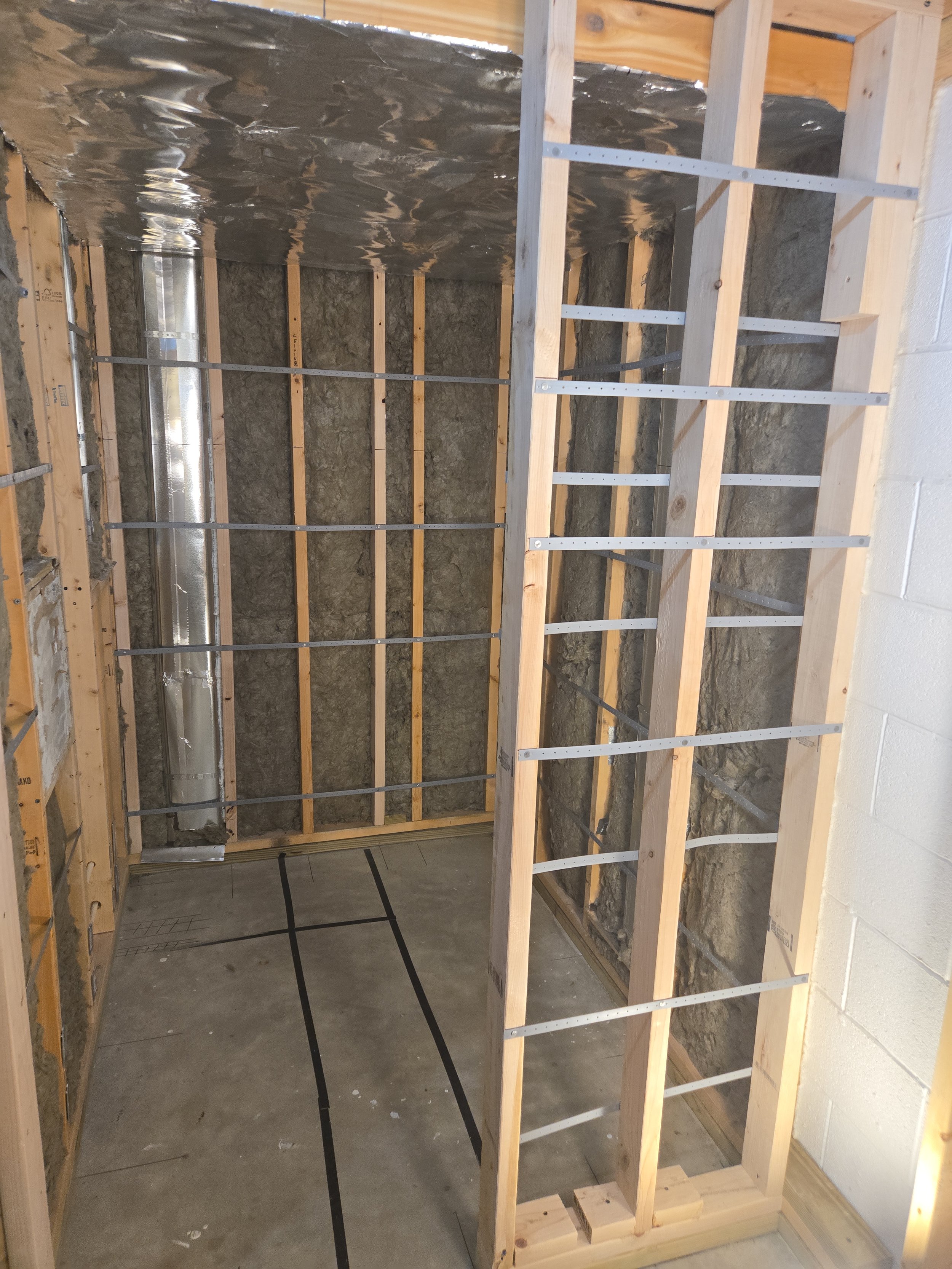 Unfinished room with wooden framing, exposed insulation, and ductwork.