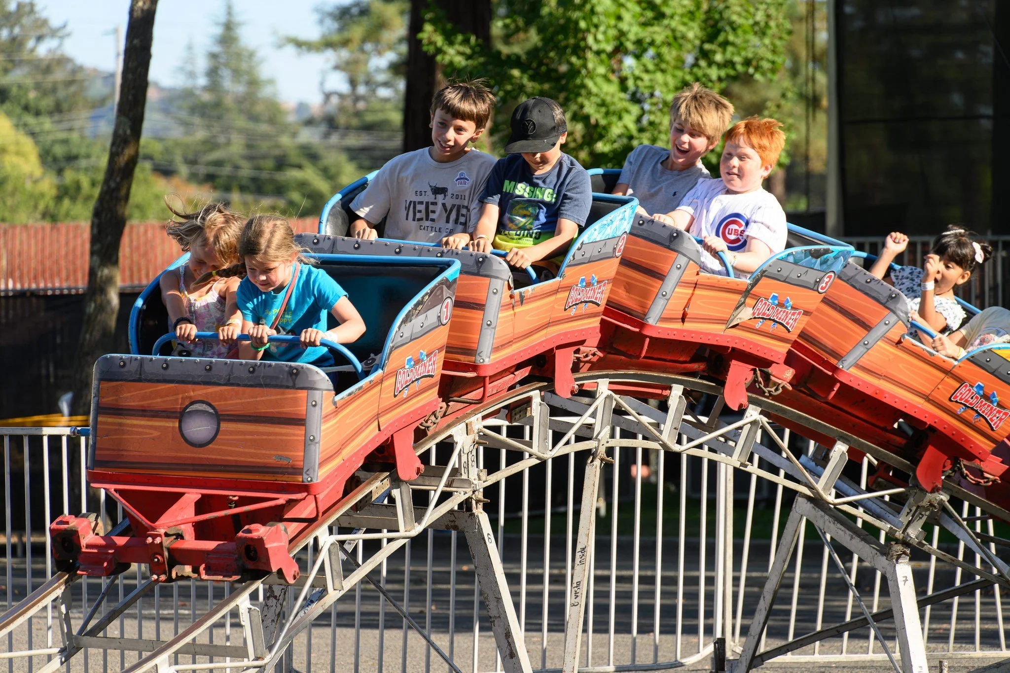 Children riding on a roller coaster at an amusement park during daytime.