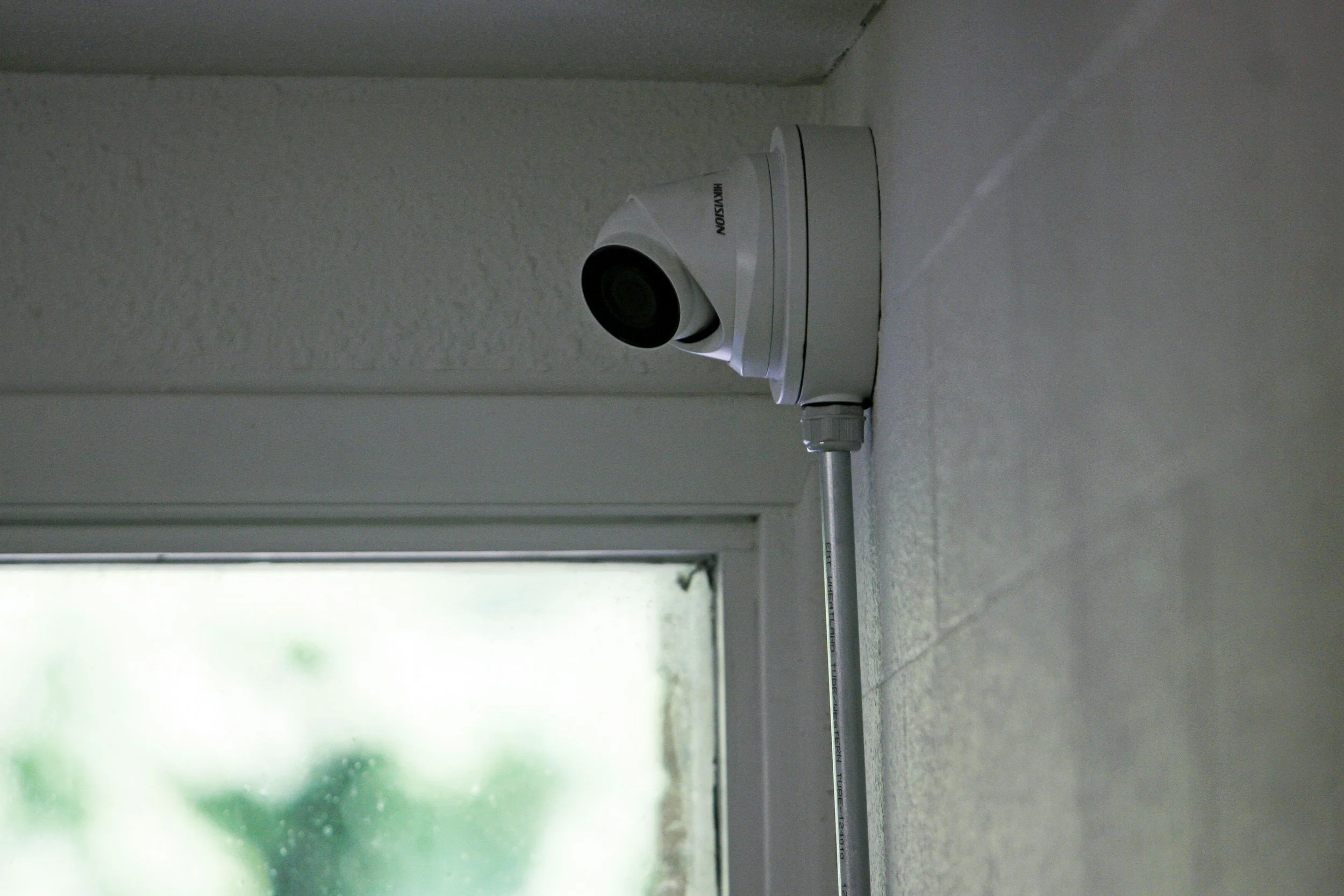 Security camera mounted on wall near window