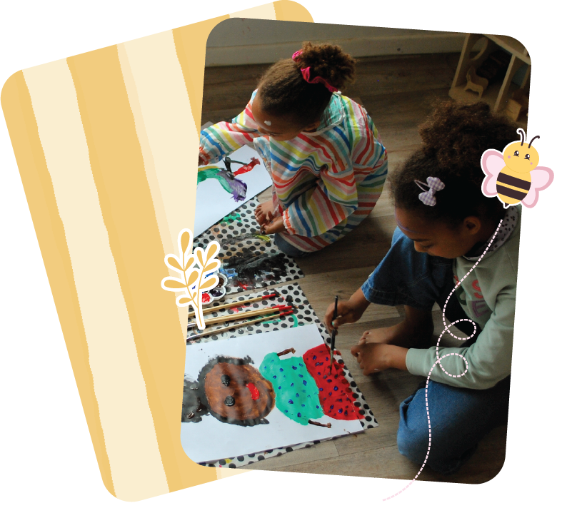 Two young girls sitting on the floor, painting colourful pictures on paper with brushes, surrounded by art supplies, in a cozy indoor setting.