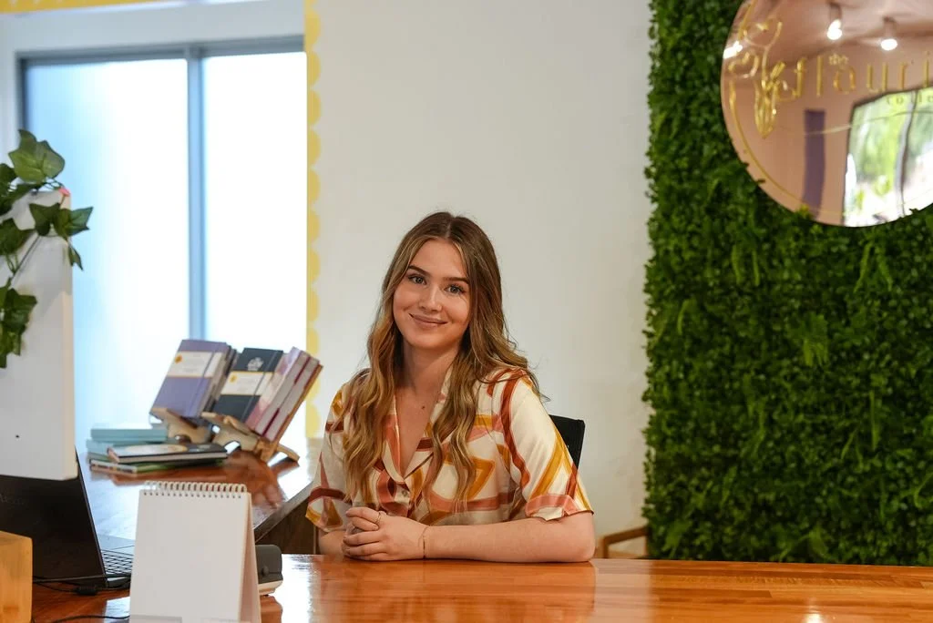 Admin support, Shayne, smiling at the camera from behind the flourish desk.