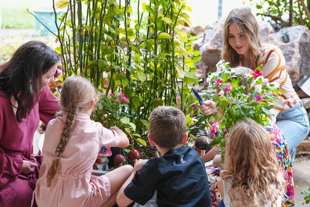 The Flourish Collective, group work with a clinician showing children plants and mushrooms in a garden.