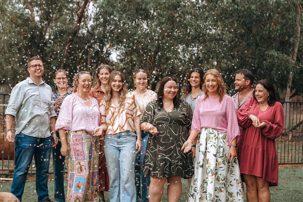Group of diverse smiling people celebrating outdoors with confetti in the air.