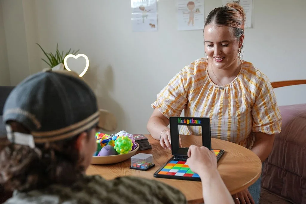 Clinician and a young man playing a colourful board game.