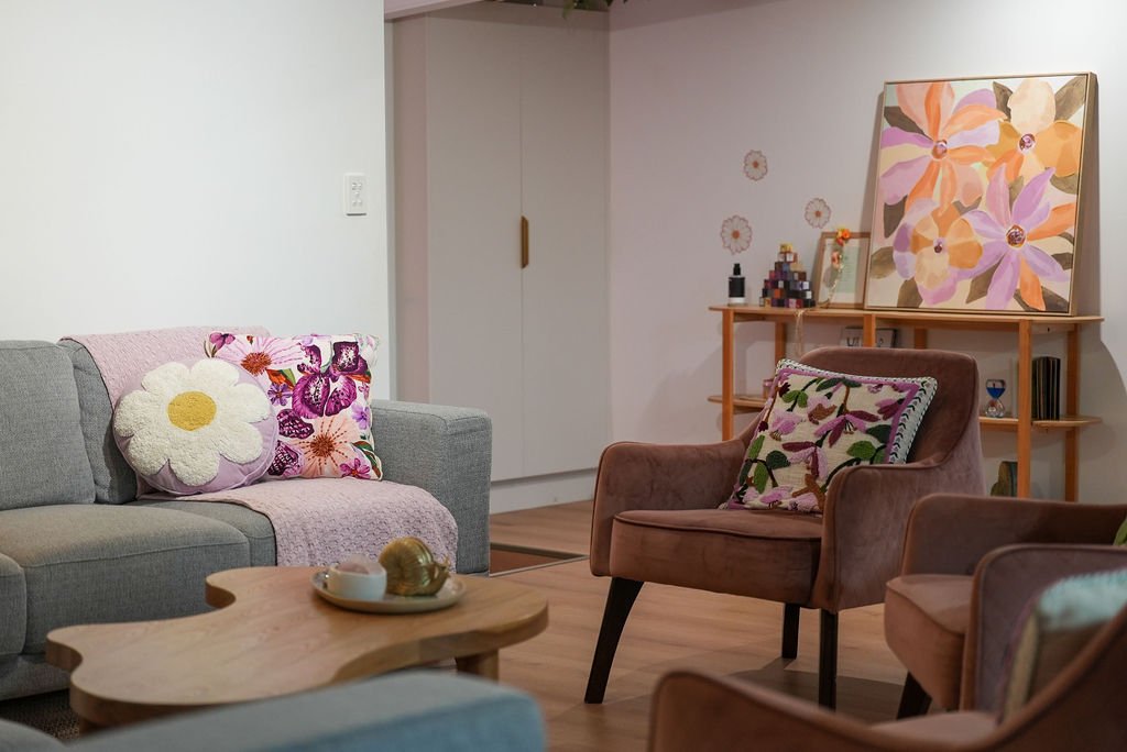 Flourish collective waiting area, an orange chair with a floral throw pillow and gray blanket.
