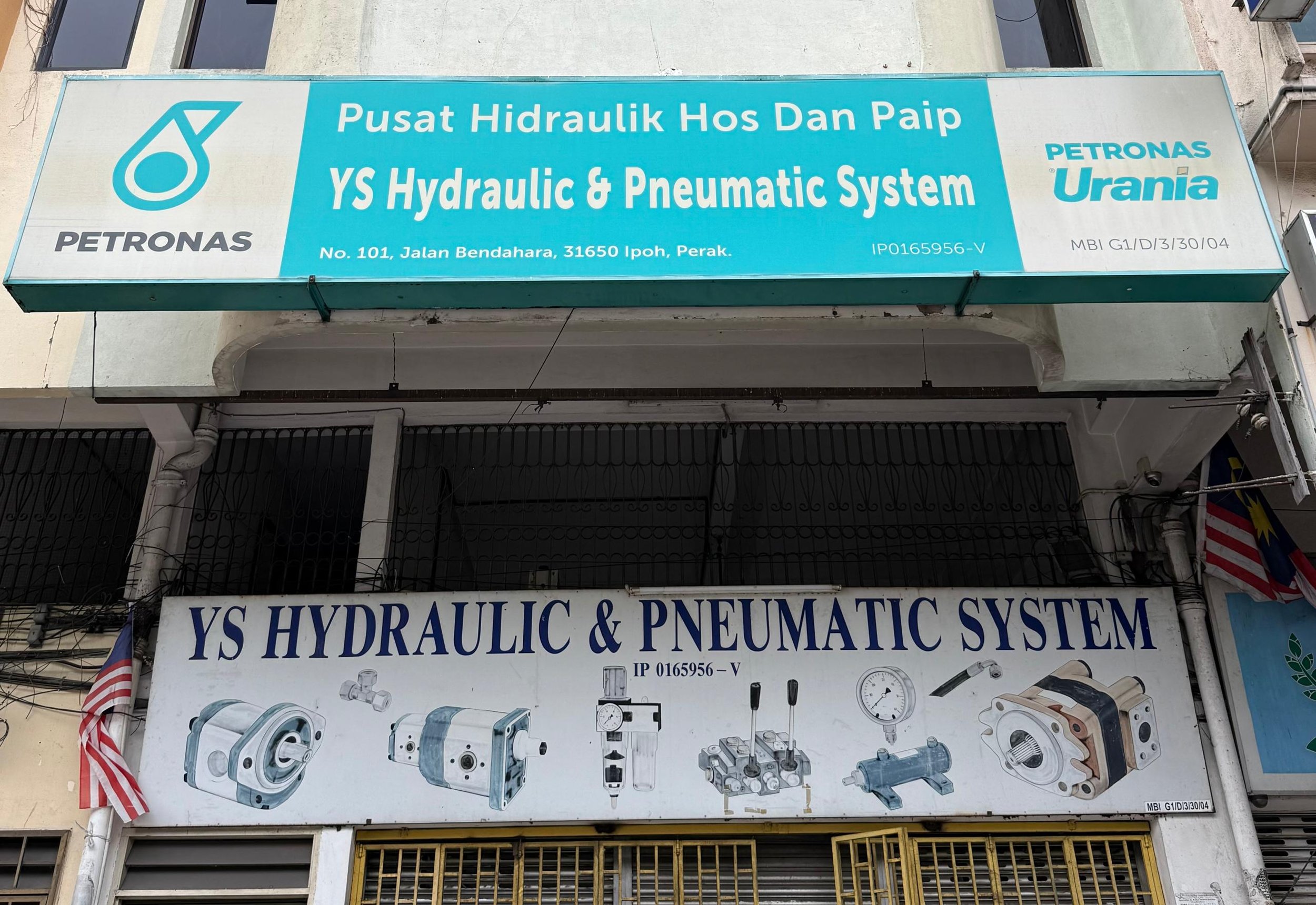 Signboard advertising a hydraulic and pneumatic system shop, with company name PETRONAS Urania, located at No. 101, Jalan Bendahara, Ipoh, Perak. The sign includes illustrations of various hydraulic and pneumatic components.