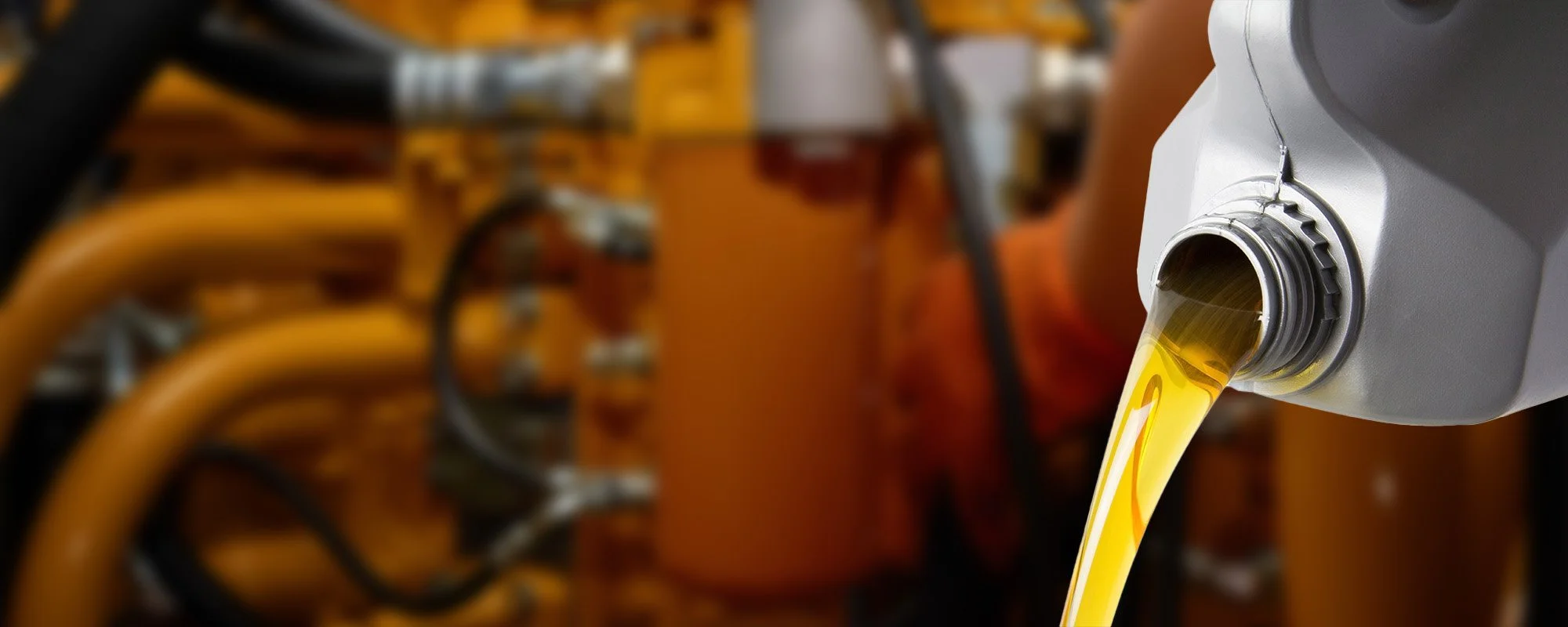 A container pouring yellow oil into a machine in a workshop.