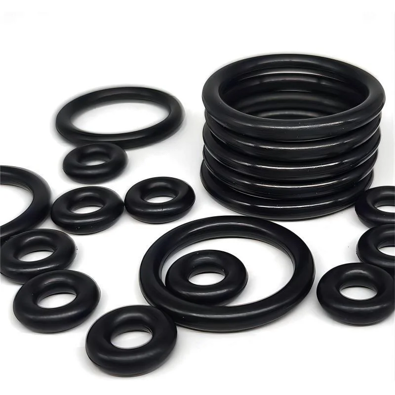 Black rubber O-rings of various sizes, some stacked and some scattered on a white background.