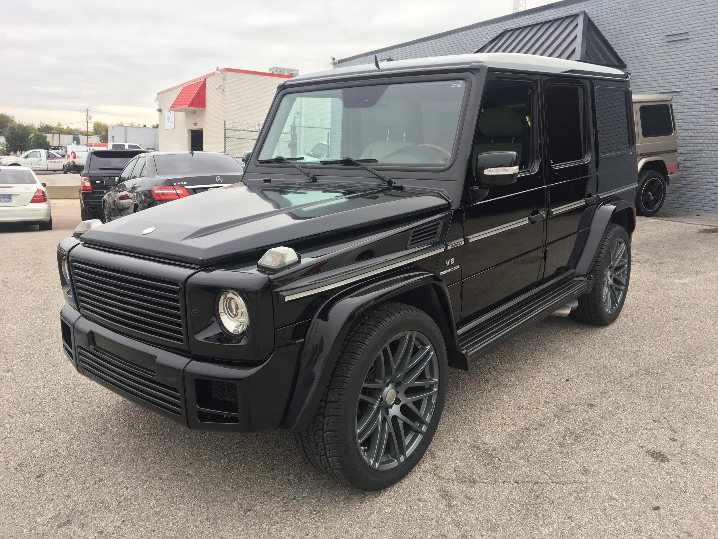 Black Mercedes-Benz G-Class SUV with custom wheels parked in lot.