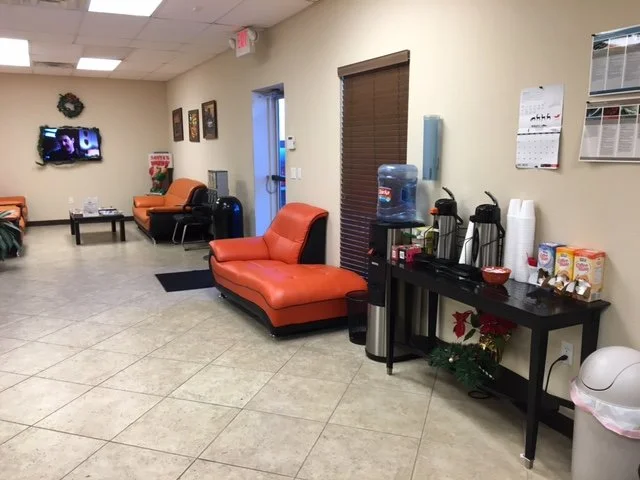 Waiting area with orange couches, water dispenser, coffee station, and Christmas decorations.