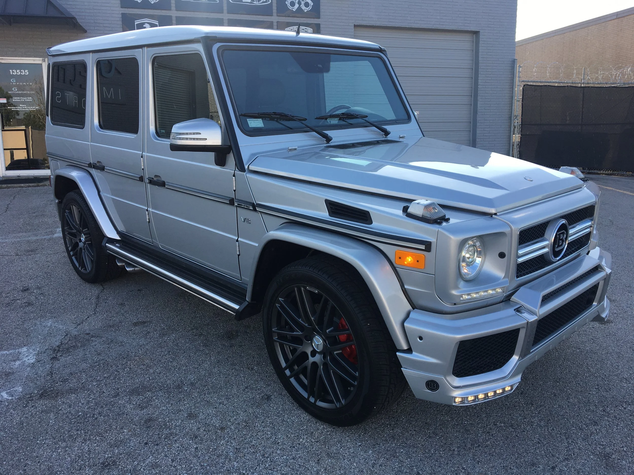 Silver modified Mercedes-Benz G-Class SUV parked outdoors, featuring custom rims, body modifications, and additional styling elements.