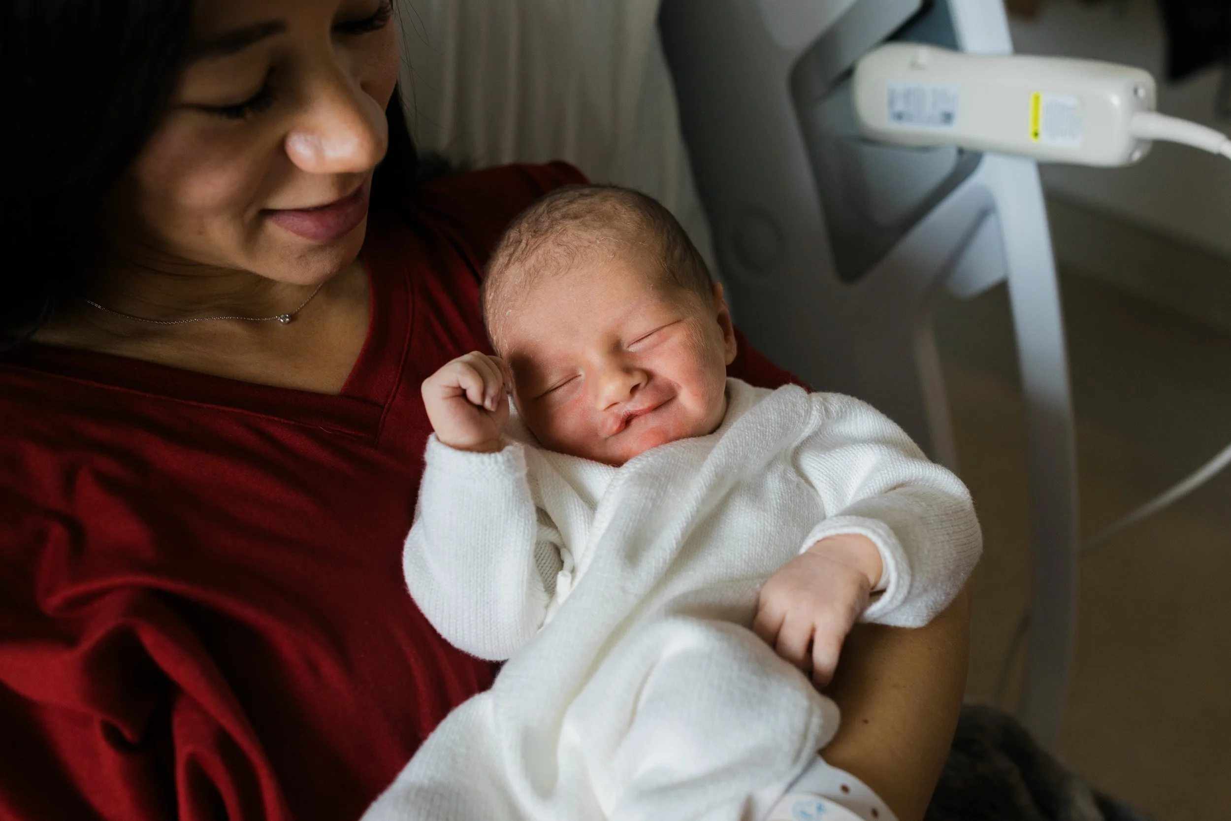 Newborn baby wrapped in a striped blanket lying in a hospital bassinet.