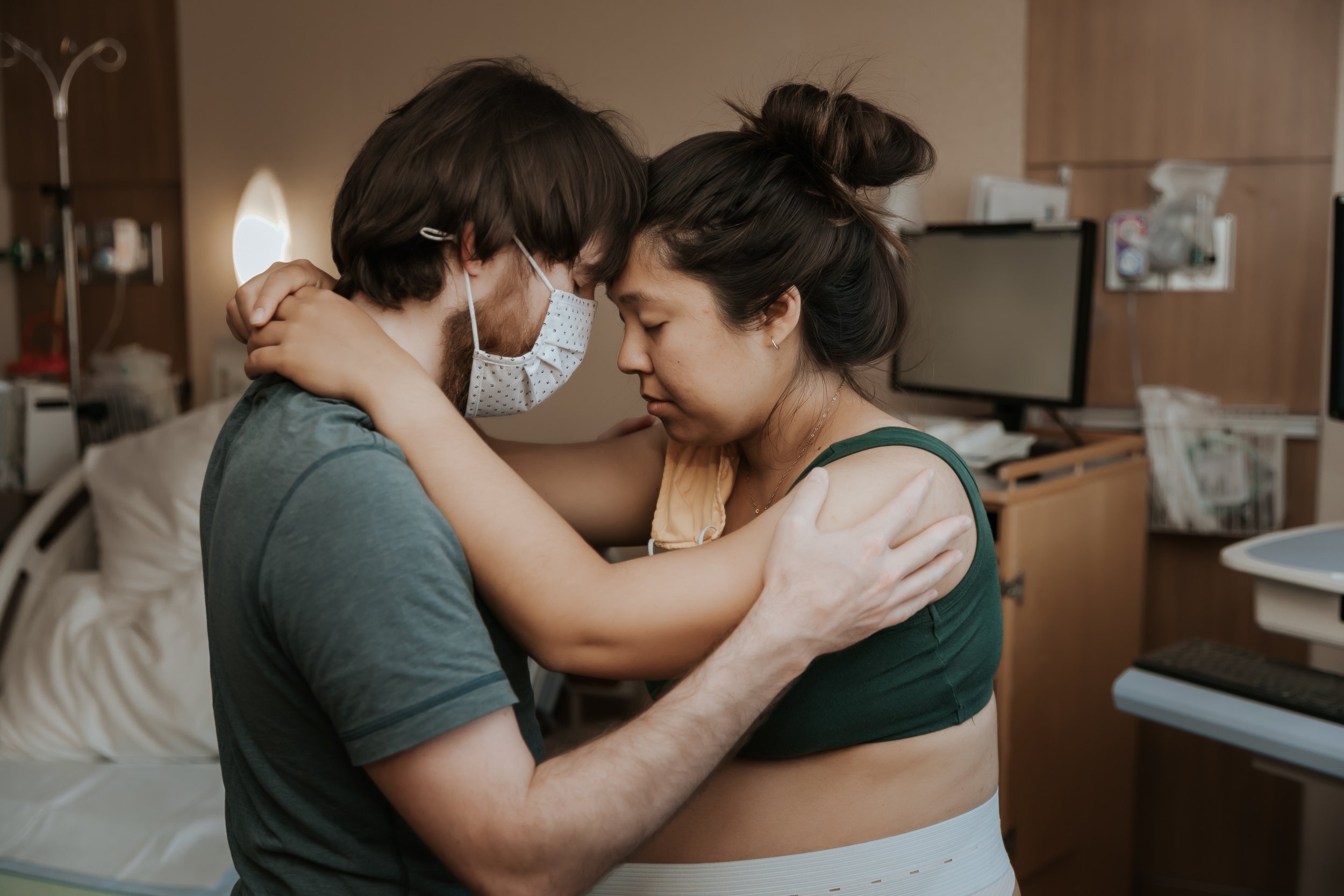 Woman in labor supported by partner. Taken by Bay Area Birth Photographer Paige Driscoll.