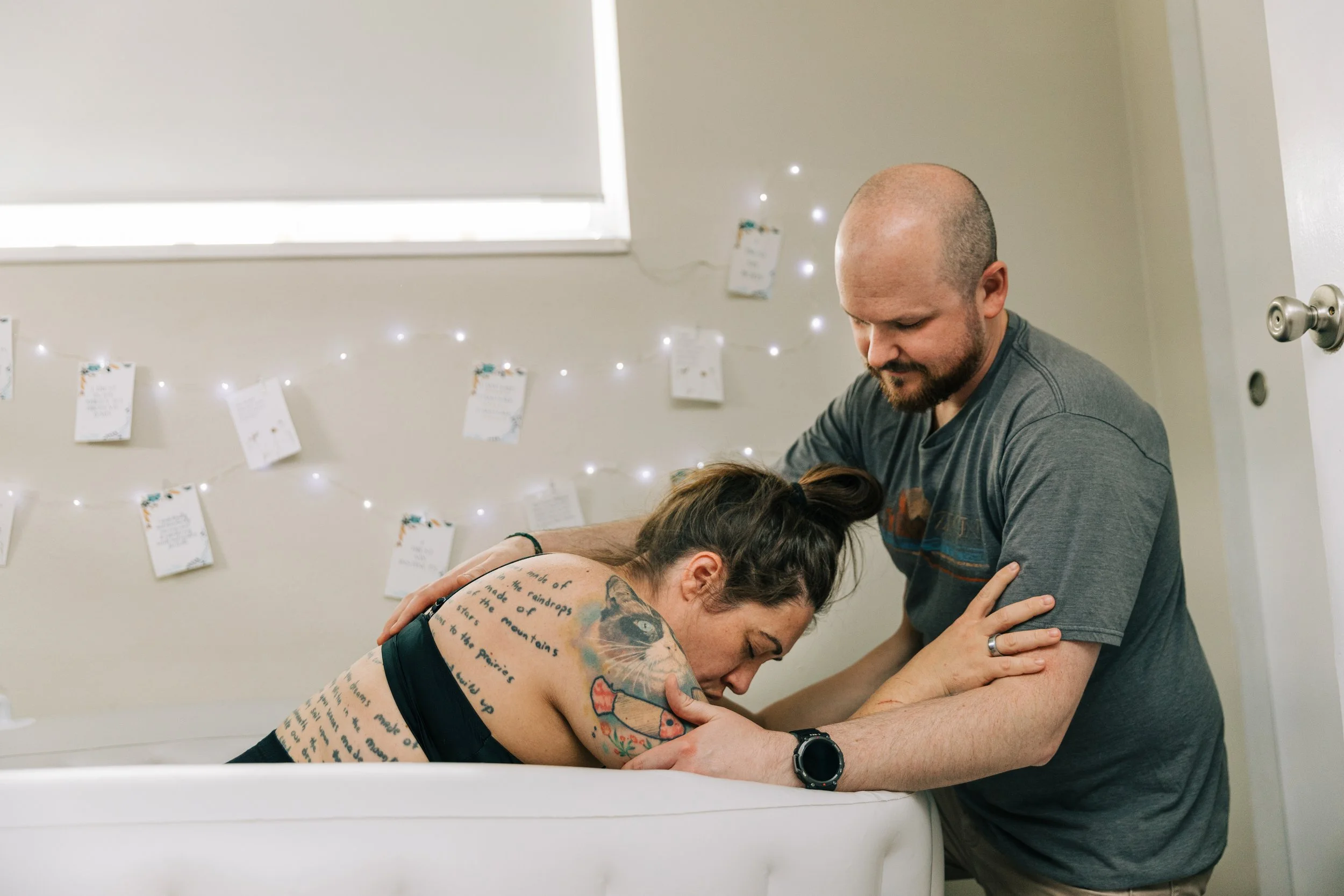 Woman in labor supported by her partner at home in a birthing tub.