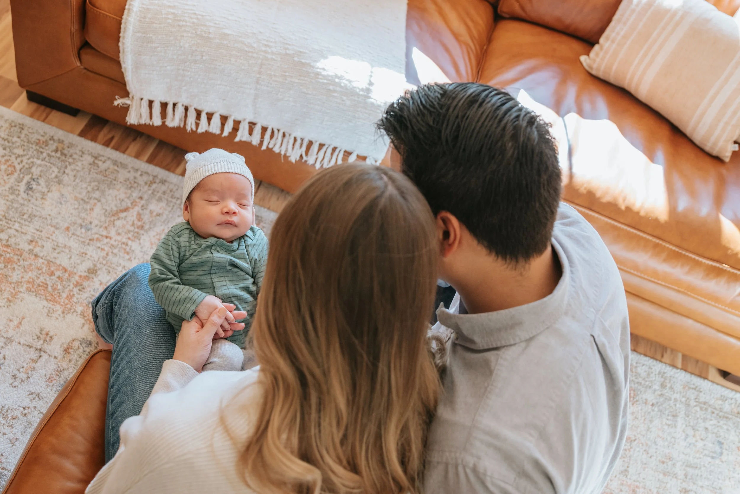 Mexican family holding their newborn son in a well lit living room.