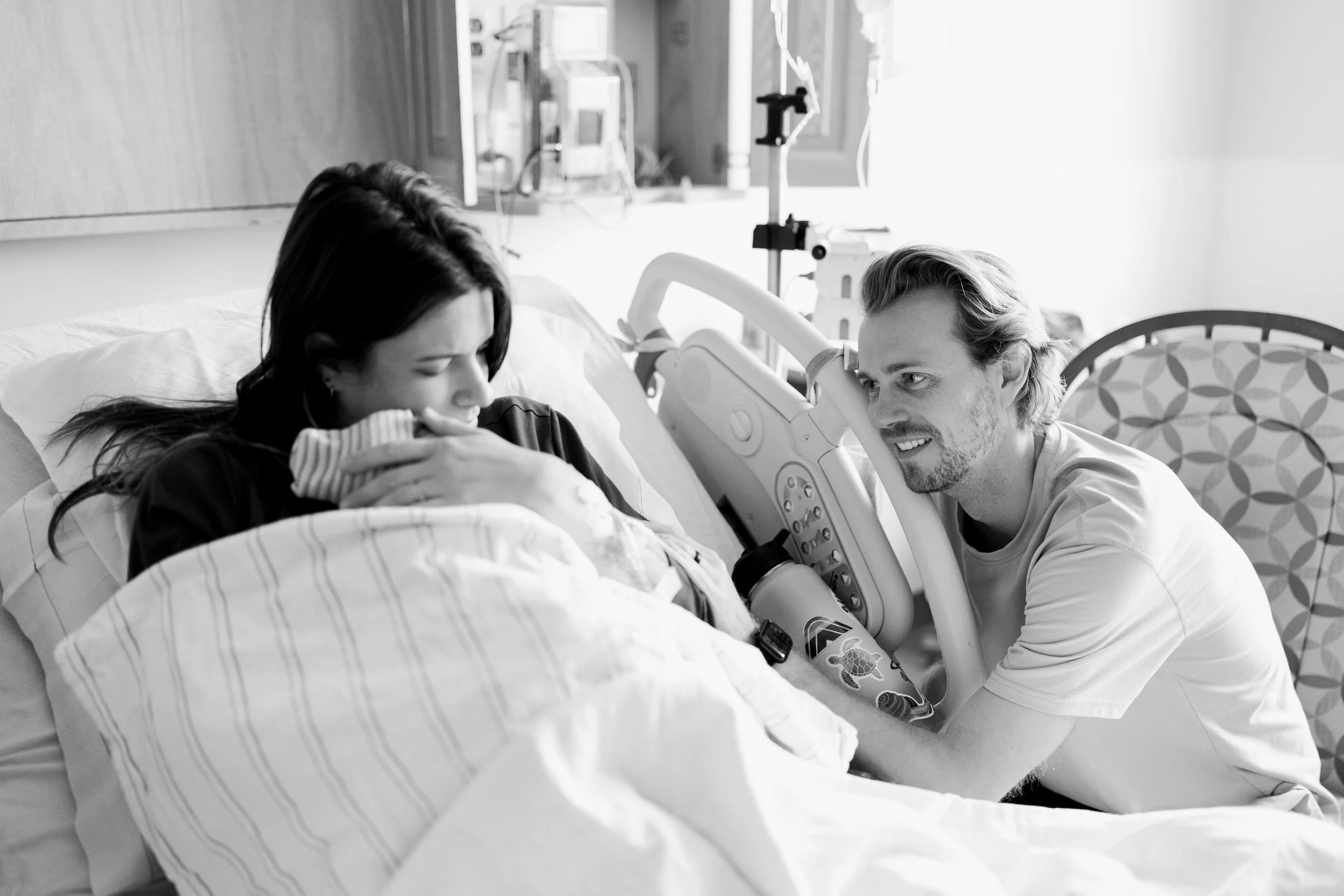A dad gazing lovingly at his wife and new baby