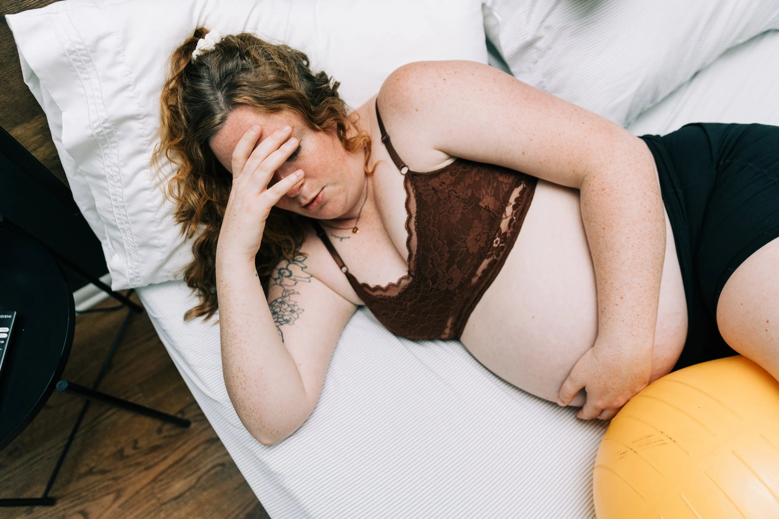 White woman with red hair laboring in bed with a peanut ball