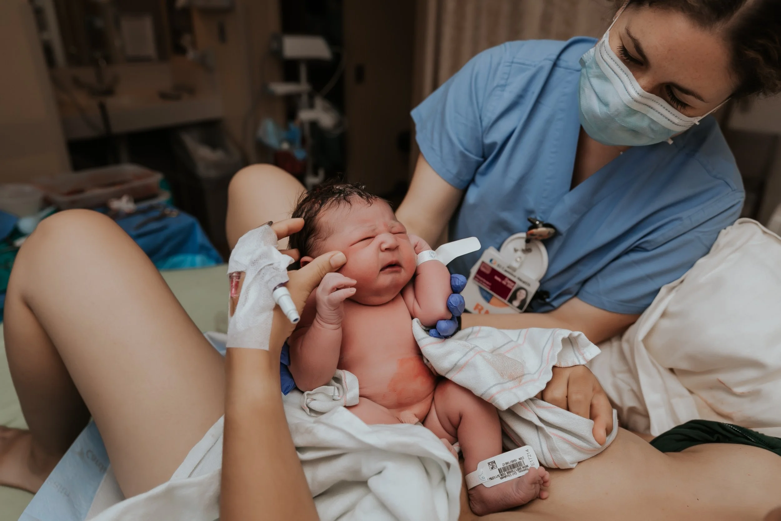 Newborn baby on lap after birth. Photo taken by Bay Area Birth Photographer Paige Driscoll.