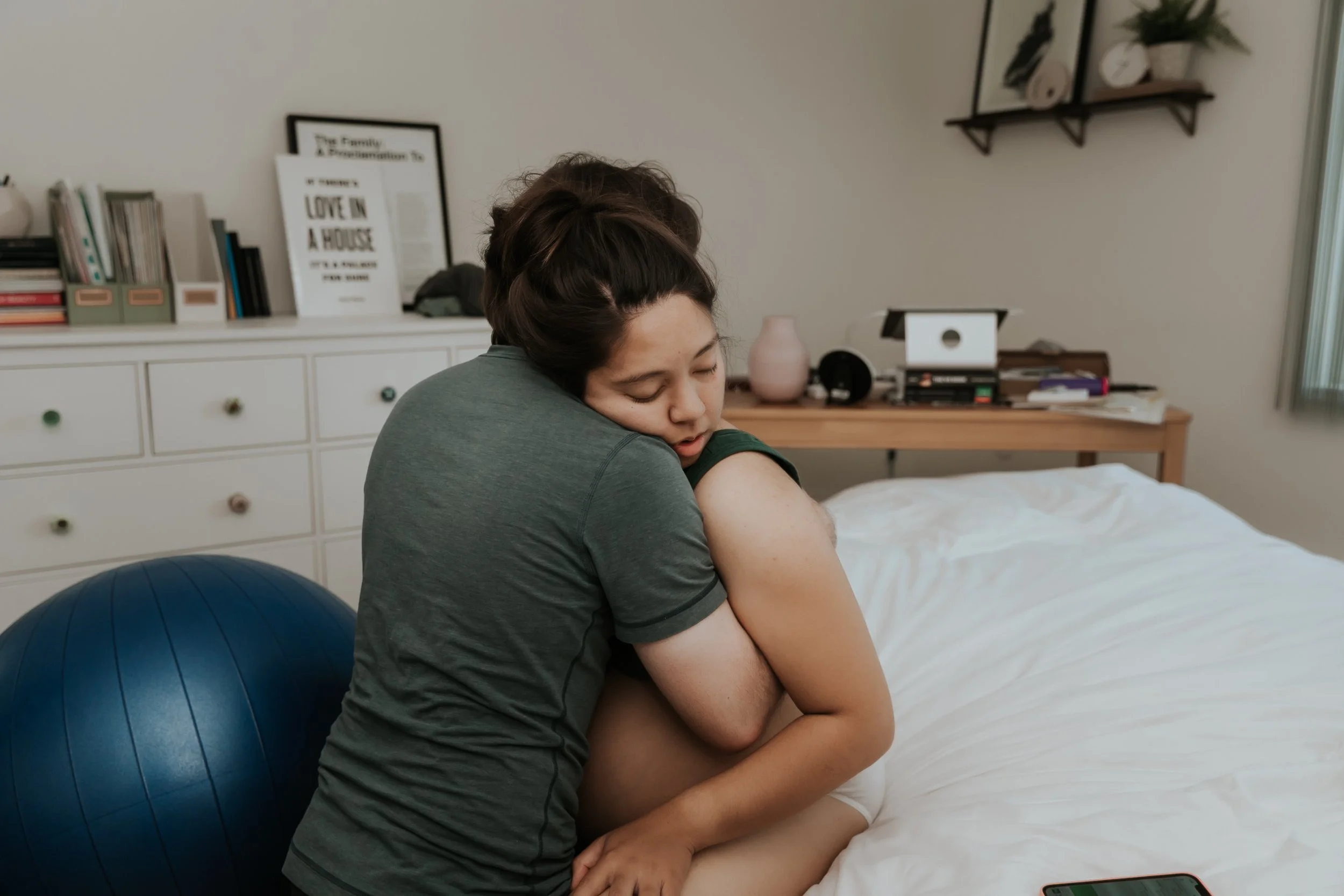 Woman in labor supported by partner. Taken by Bay Area Birth Photographer Paige Driscoll.