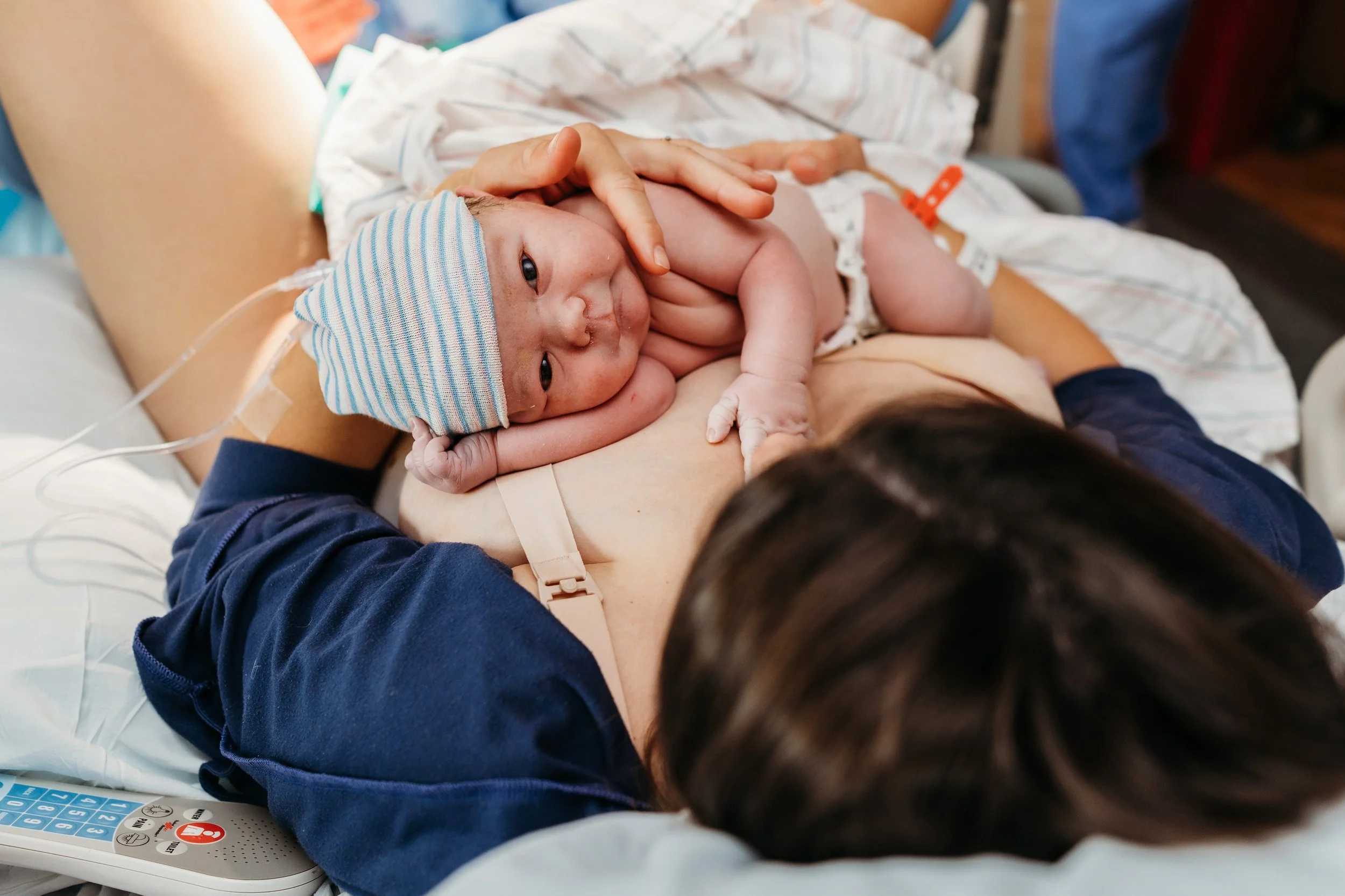 Newborn baby staring right at camera after being placed on his mom's chest at the hospital.